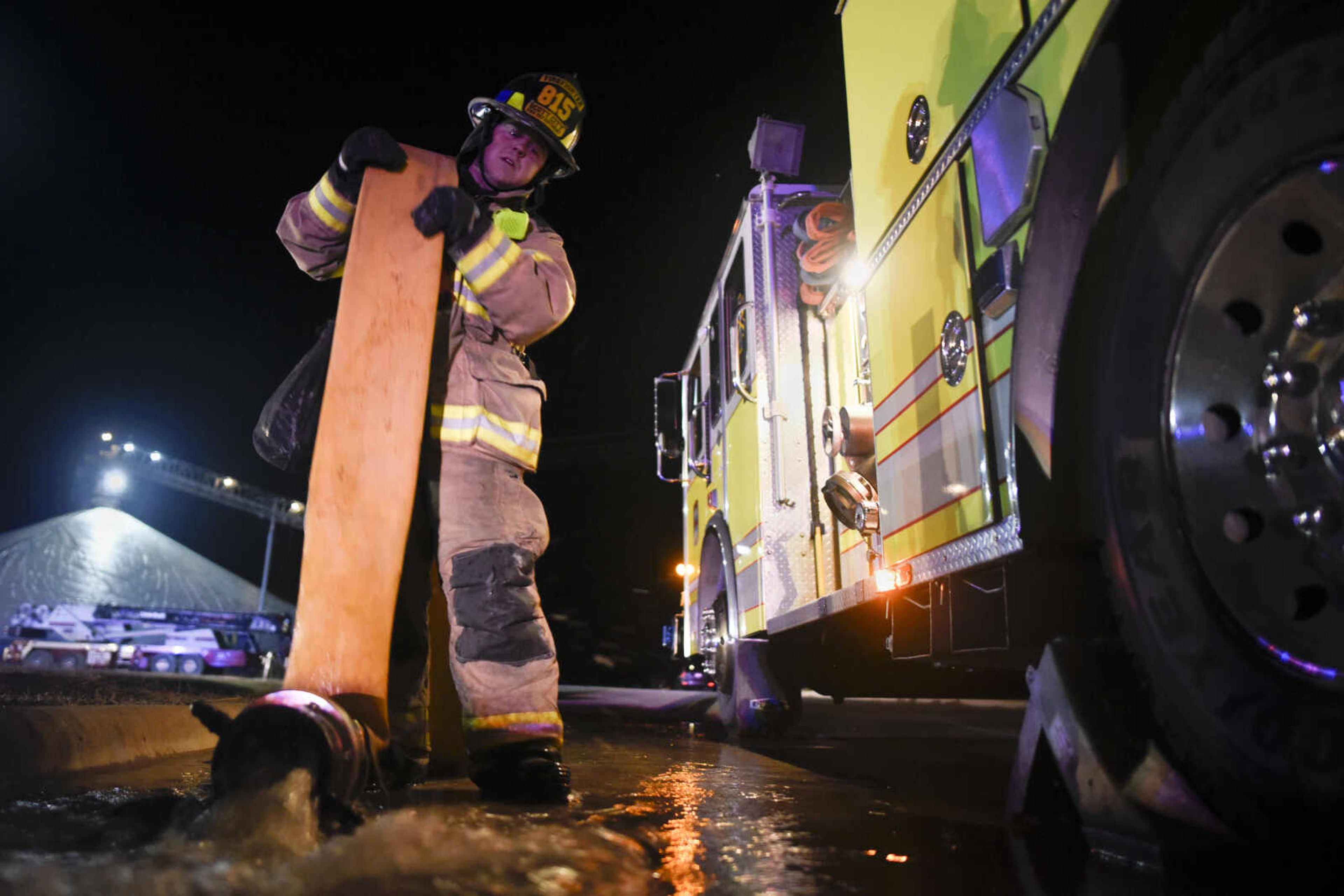 Scott City firefighter Braden Brown drains water from a line after working to contain a fire Tuesday at Midwest Grain and Barge in Scott City.