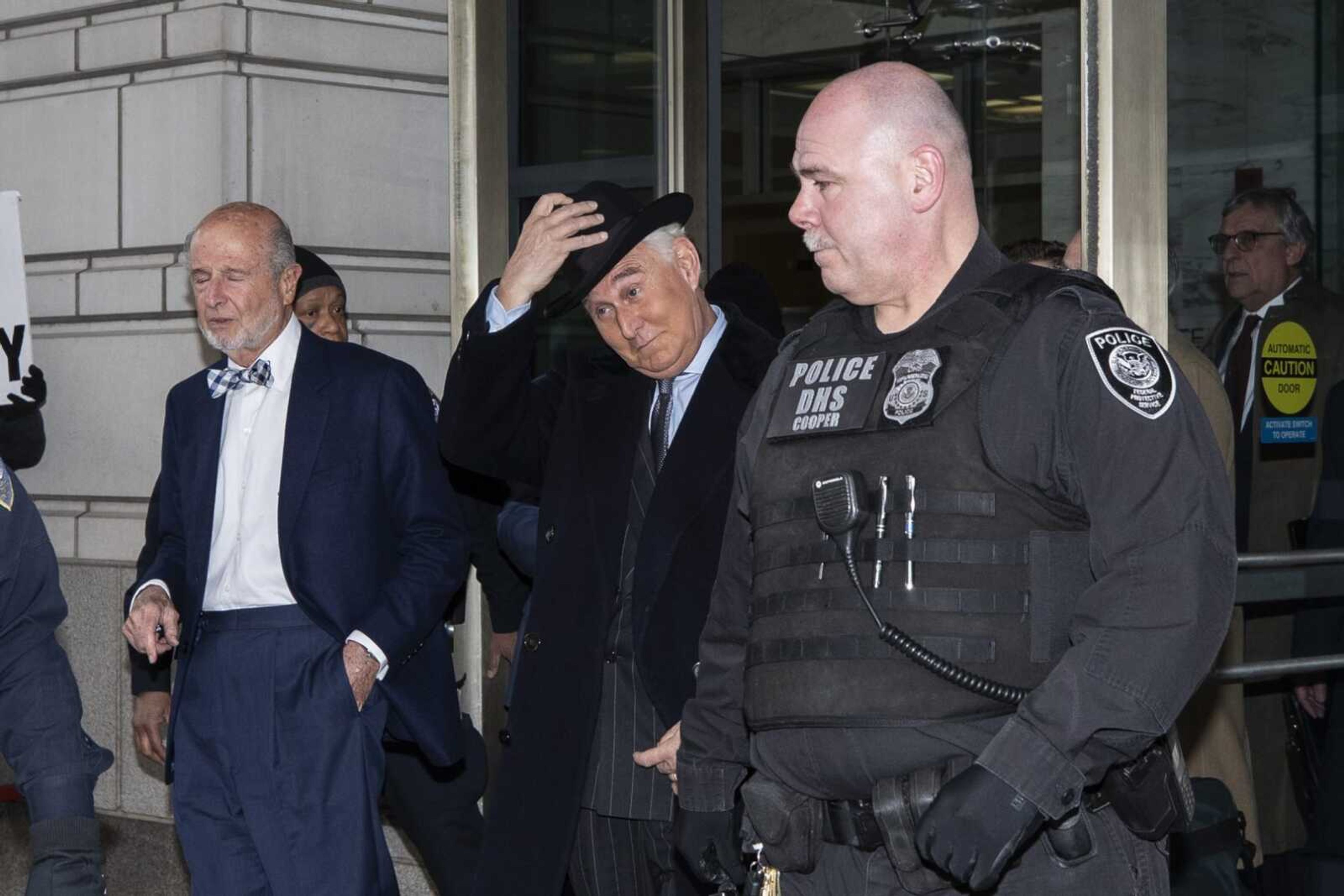 Roger Stone, center, puts his hat on as he departs after his sentencing at federal court Thursday in Washington.