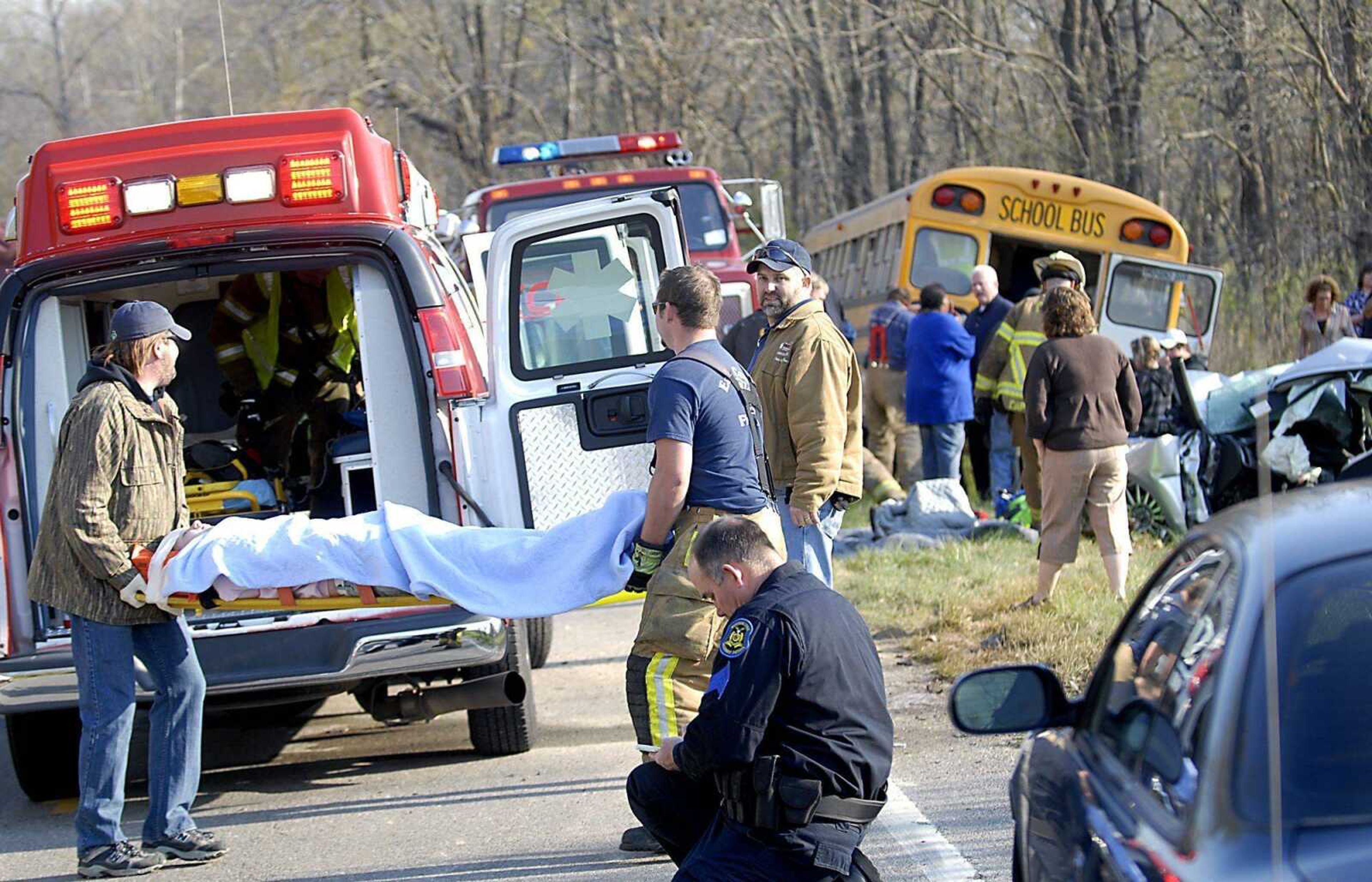 Emergency workers carry a student to an ambulance following an accident between a school bus and a Ford Focus along Highway 177 south of Nell Holcomb school Wednesday morning. (KIT DOYLE ~ kdoyle@semissourian.com)