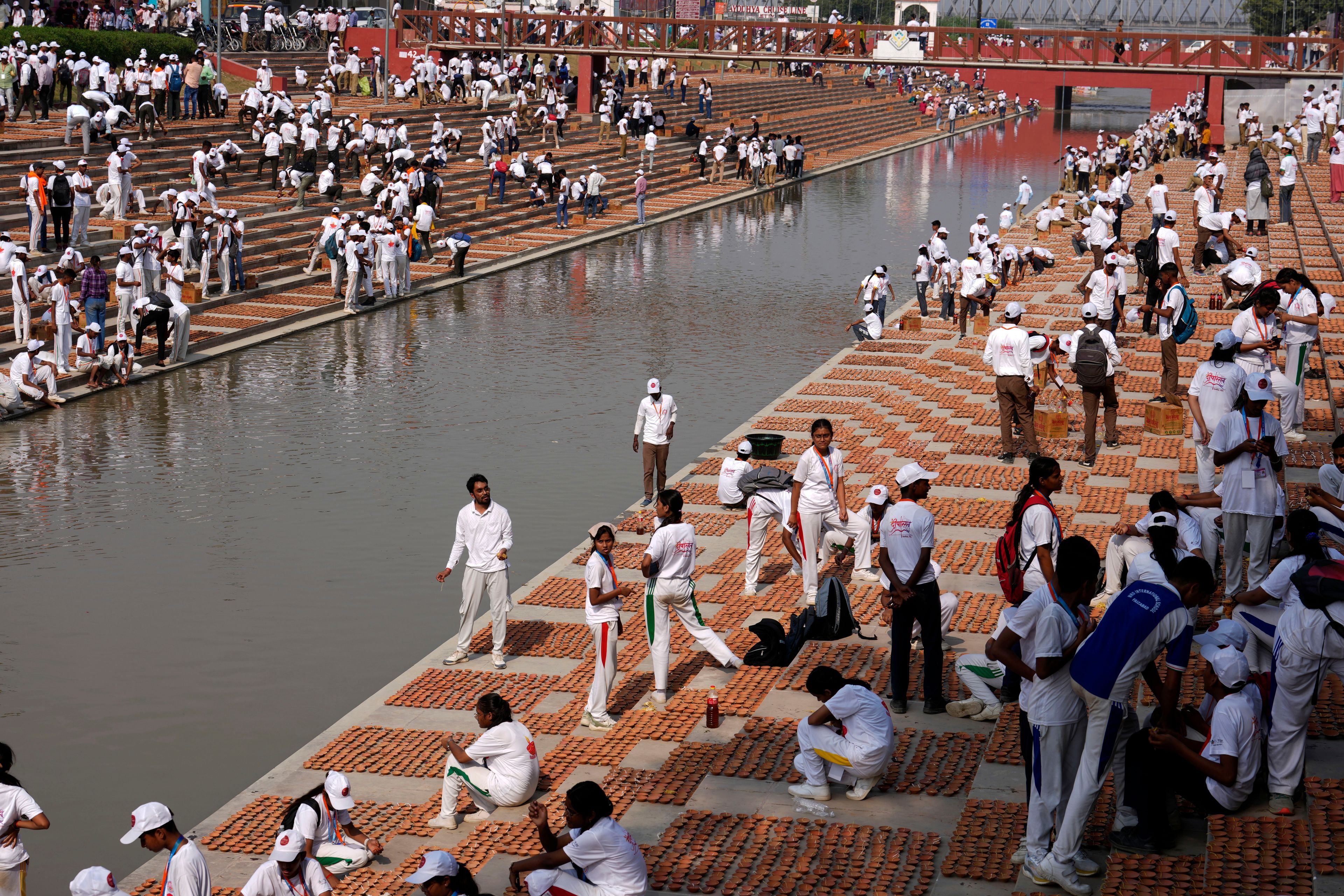 Volunteers place earthen lamps on the banks of the Saryu river on the morning of Deepotsav celebrations, an event organized by the Uttar Pradesh state government on the eve of Diwali, in Ayodhya, India, Wednesday, Oct. 30, 2024. (AP Photo/Rajesh Kumar Singh)