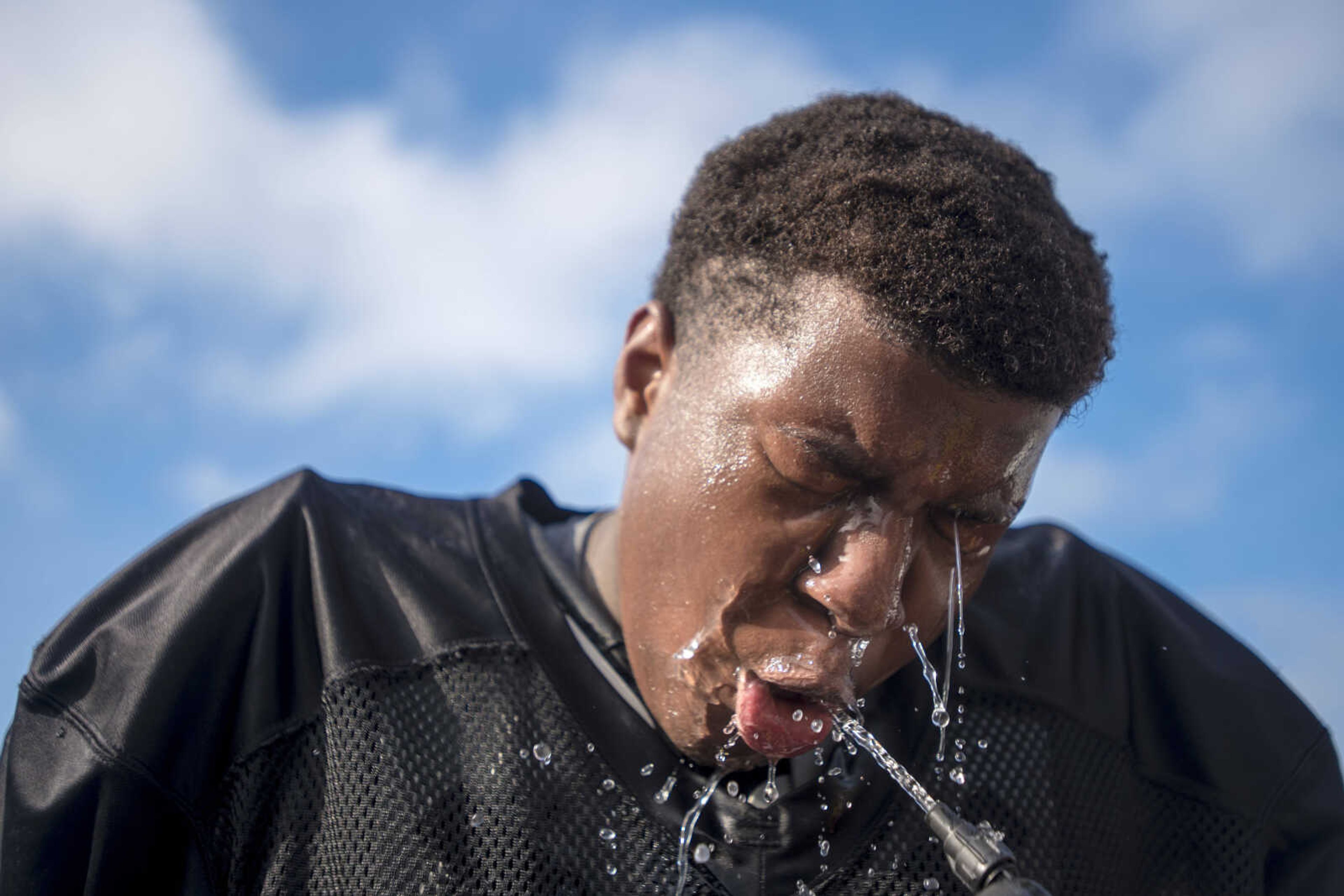 Water bounces off the face of Cape Central lineman Landon Pearson as he drinks from the hose during a summer workout Tuesday, July 30, 2019, at Cape Central High School in Cape Girardeau.