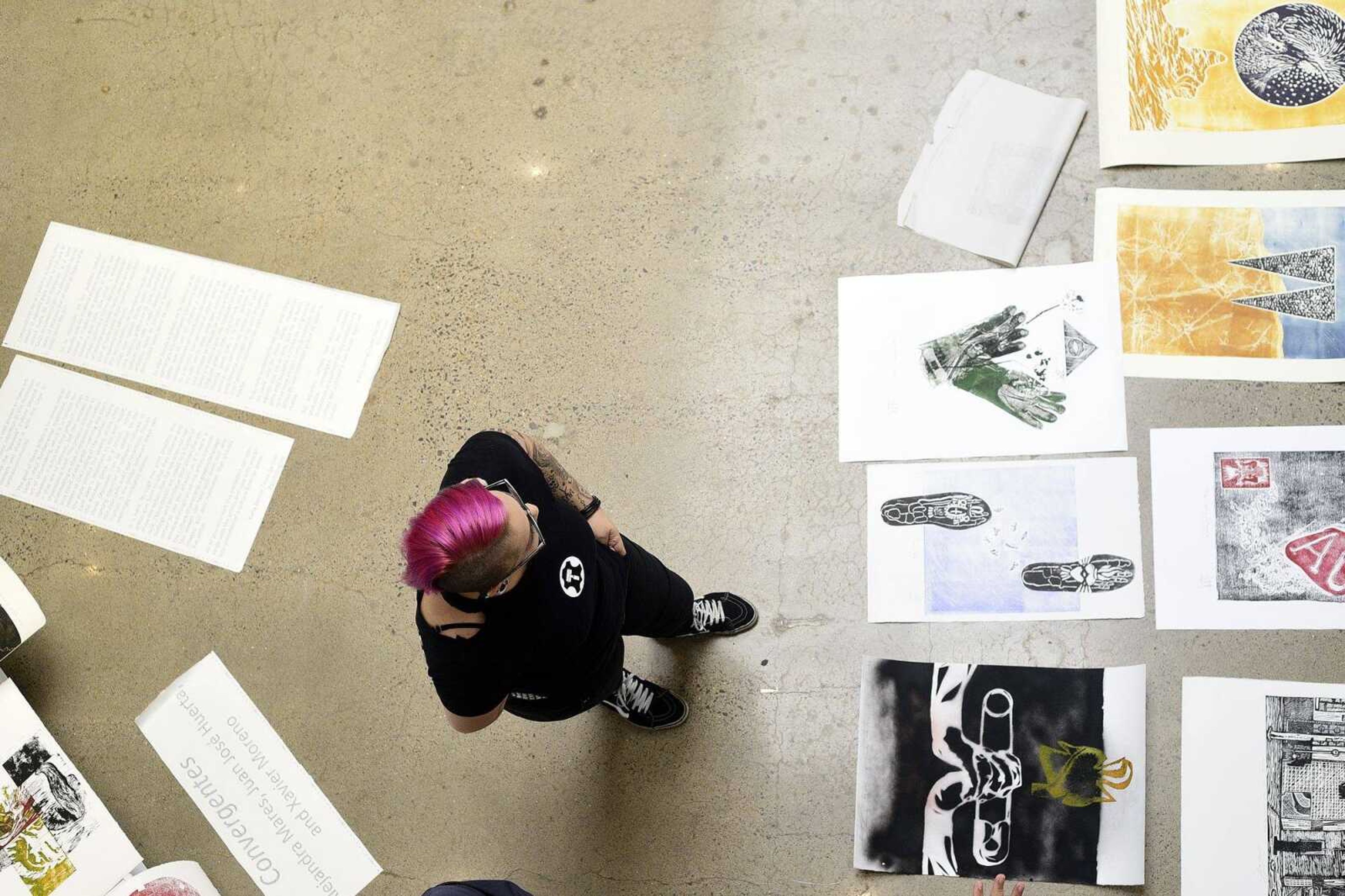 Alejandra Mares looks over art selections before hanging artwork for an upcoming show at Catapult Creative House in Cape Girardeau.