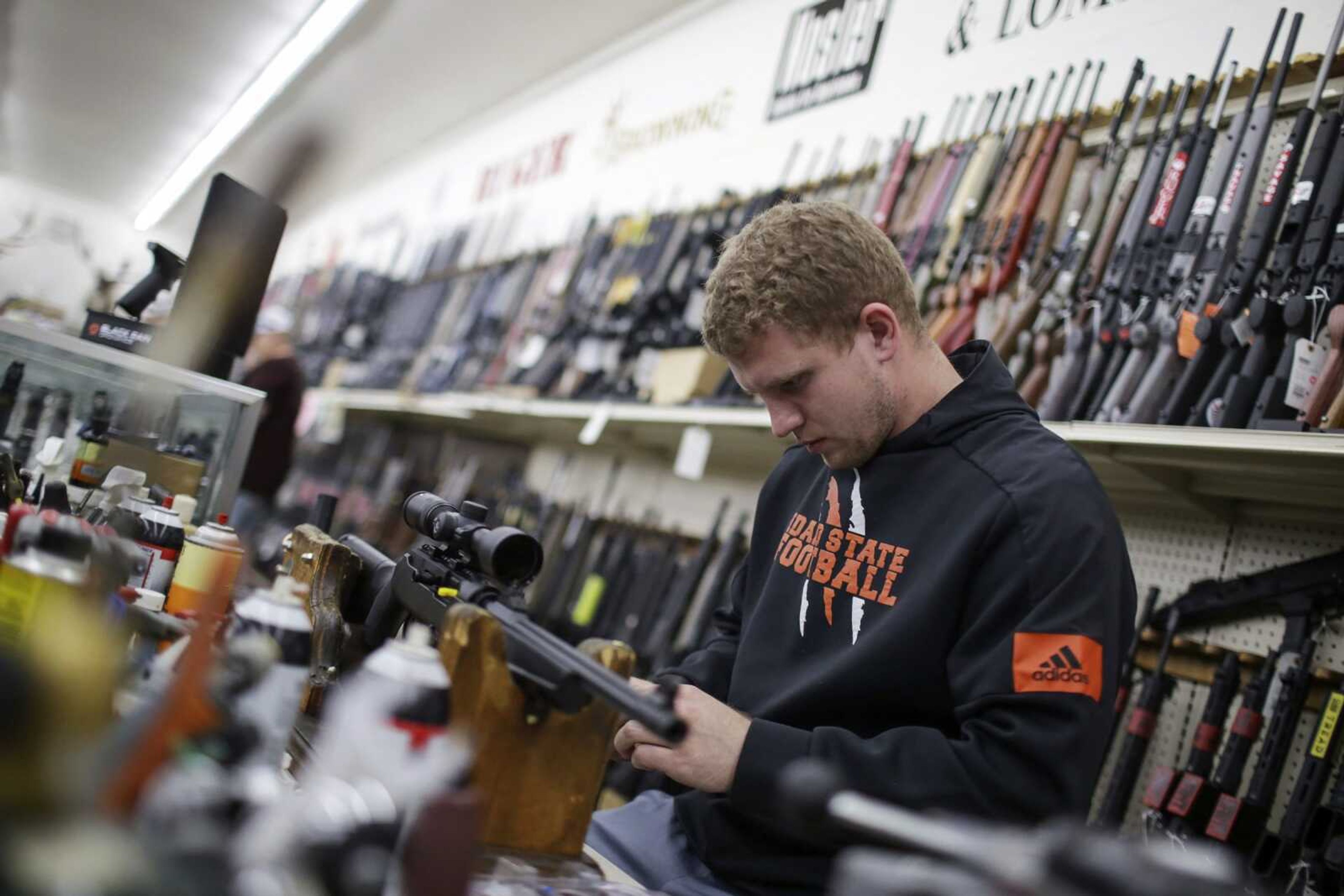 Todd Payne mounts a scope to a carbine rifle at Ross Coin and Gun on Monday, March 16, 2020, in Idaho Falls, Idaho. Just as grocery stores have been stripped bare by Americans panicked by coronavirus, guns and ammunition have started flying off the shelves. (John Roark/The Idaho Post-Register via AP)