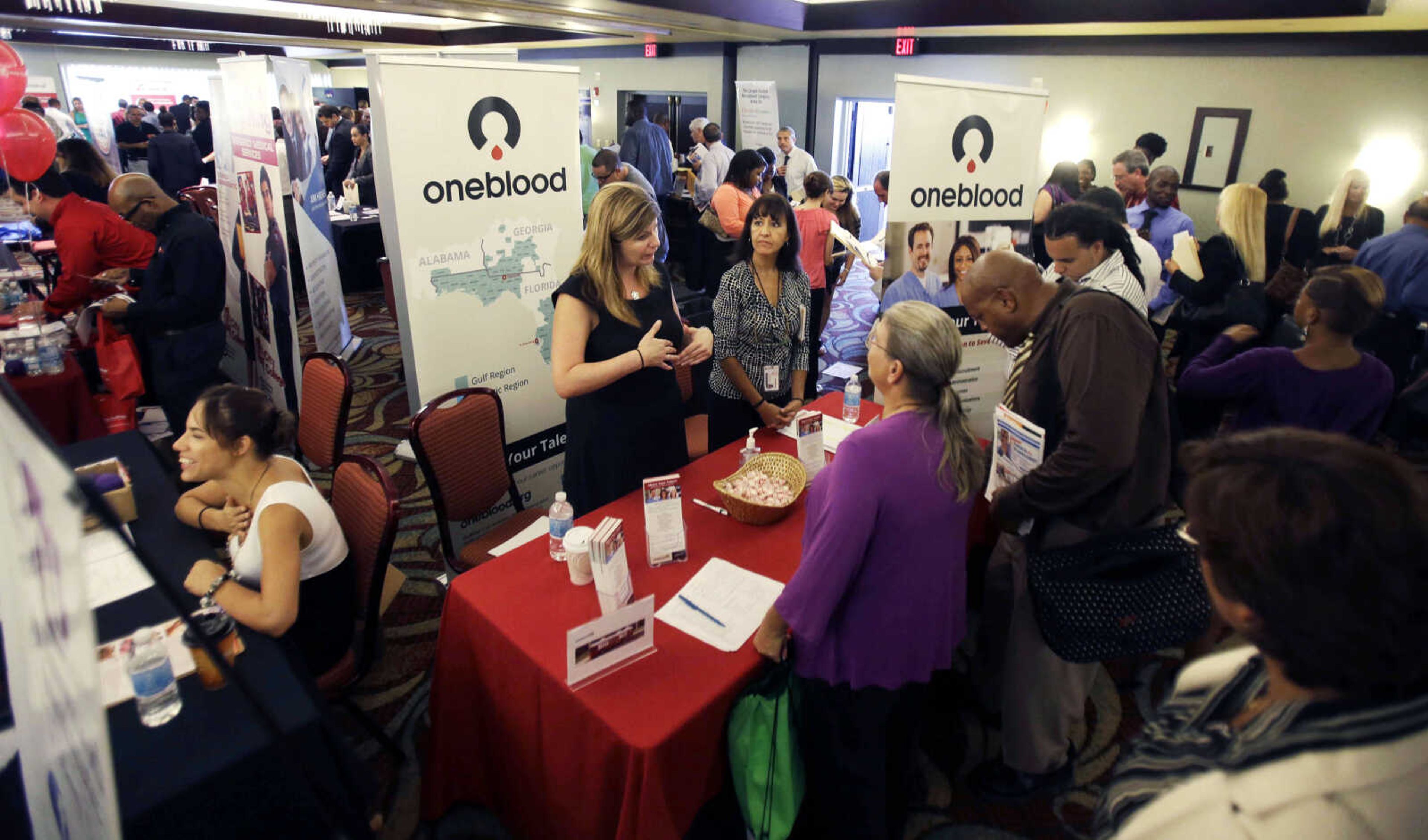 FILE - In this Aug. 14, 2013, file photo, people check out opportunities during a job fair in Miami Lakes, Fla. U.S. employers added 169,000 jobs in August, and the unemployment rate dropped to 7.3 percent, the lowest in nearly five years, according to the Labor Department, Friday, Sept. 6, 2013. (AP Photo/Alan Diaz, File)