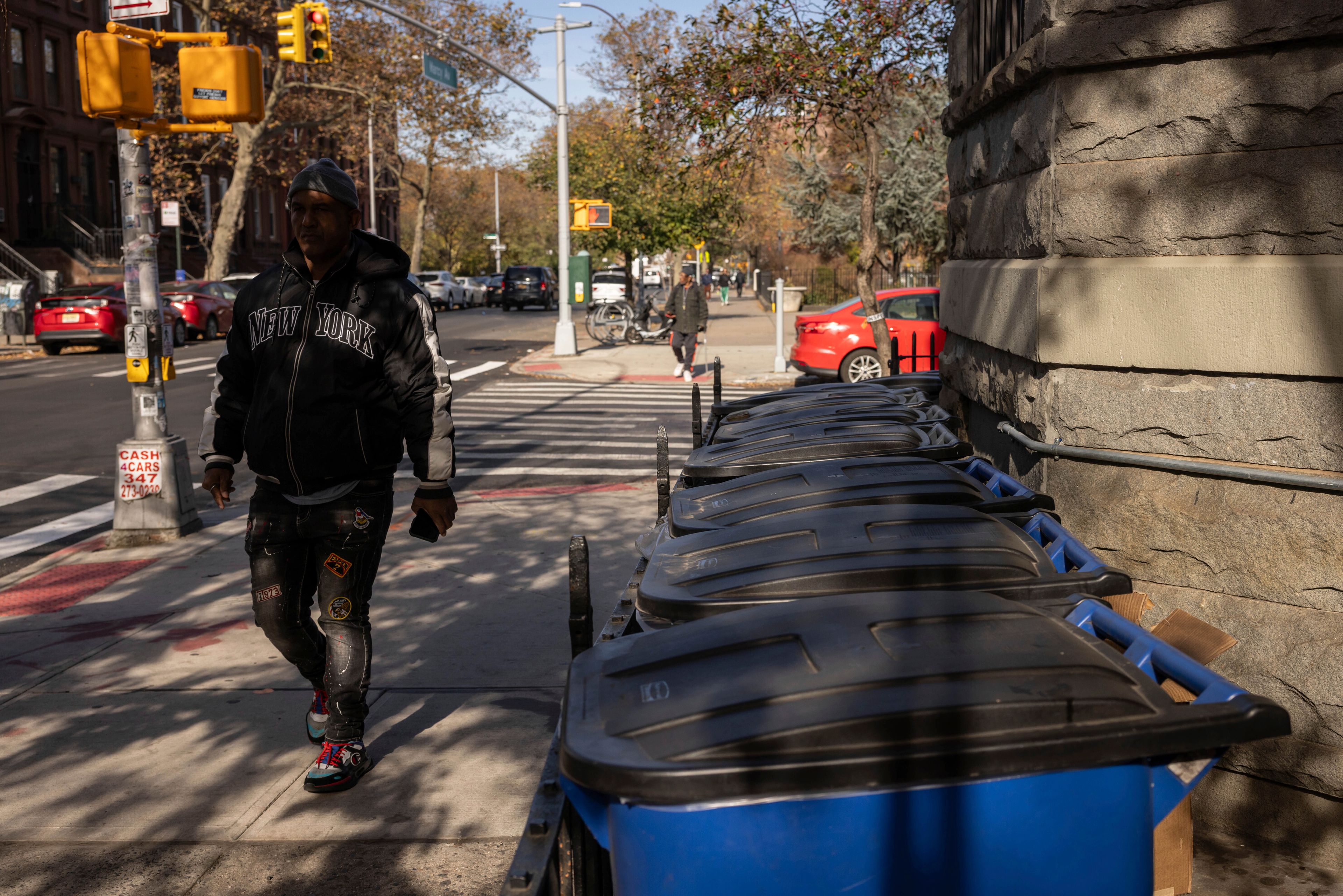 A person walks next to the trash bins, Friday, Nov. 15, 2024, in the Brooklyn borough of New York. (AP Photo/Yuki Iwamura)