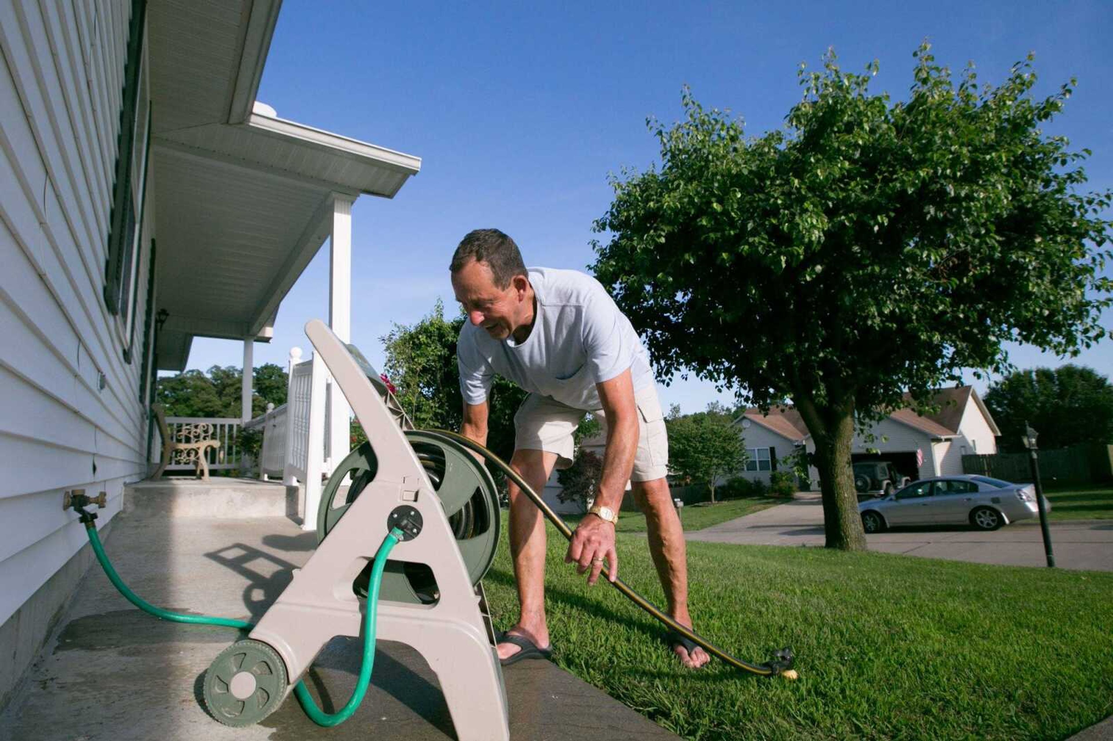 David Lane rolls up a garden hose after watering a bed of flowers in the front yard of his Hillcrest Manor subdivision home Wednesday in Cape Girardeau.