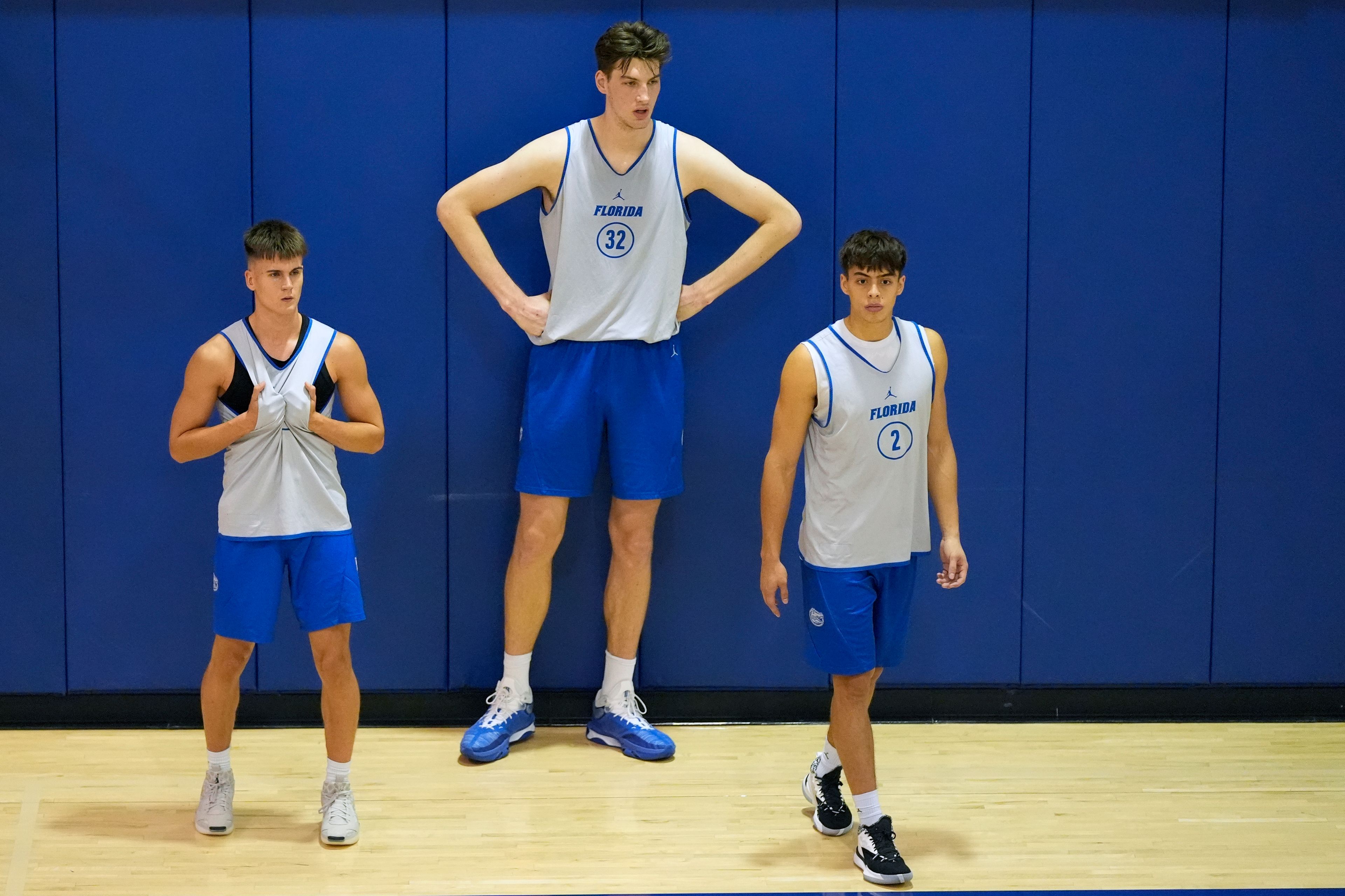 Olivier Rioux, center, a 7-foot-9 NCAA college basketball player at Florida, takes a break at practice with teammates Kajus Kublickas, left, and Kevin Pazmino (2), Friday, Oct. 18, 2024, in Gainesville, Fla. (AP Photo/John Raoux)