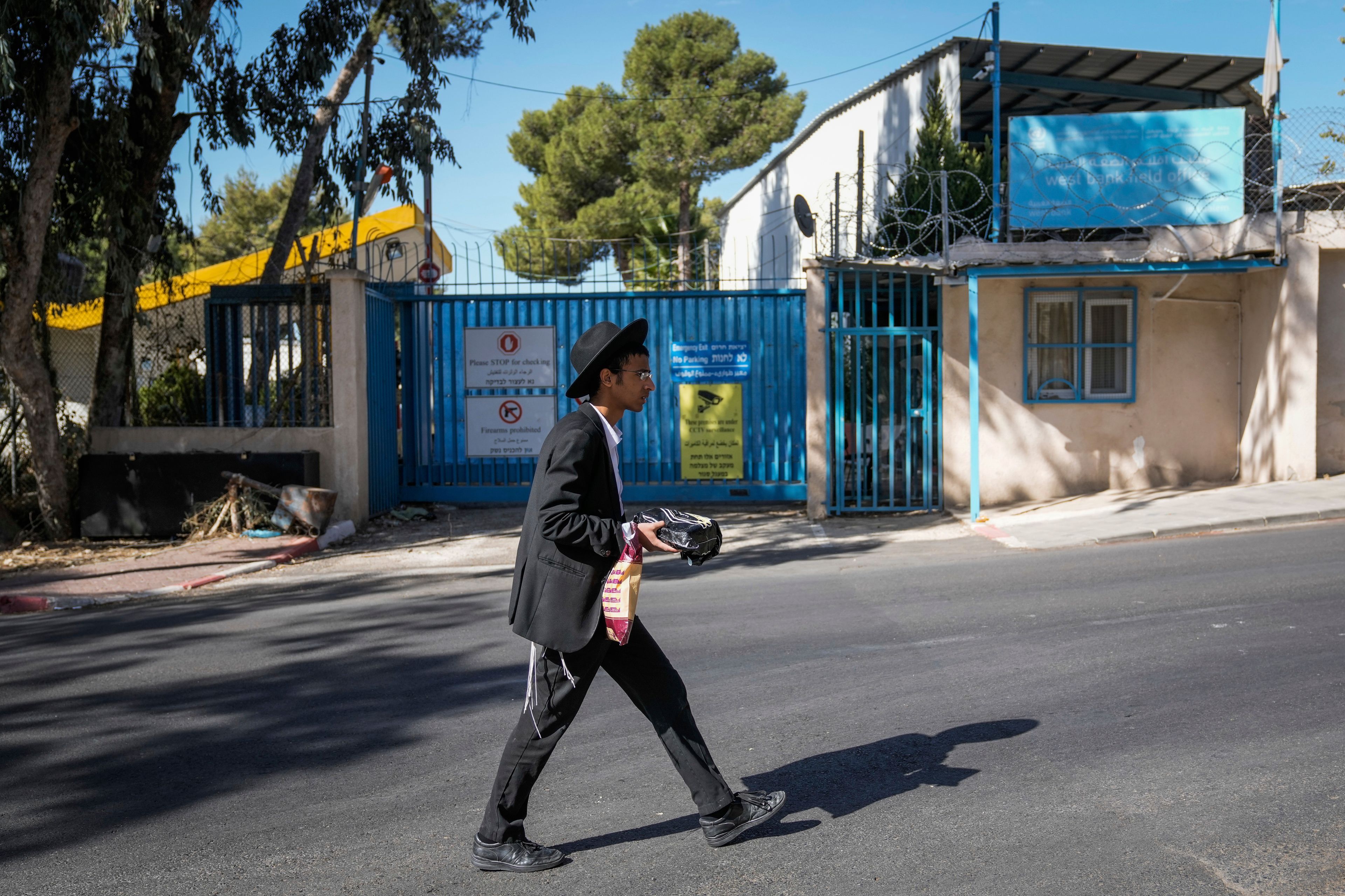 An ultra-Orthodox Jewish man walks past the east Jerusalem compound of UNRWA, the U.N. agency helping Palestinian refugees, Tuesday, Oct. 29, 2024. (AP Photo/Mahmoud Illean)