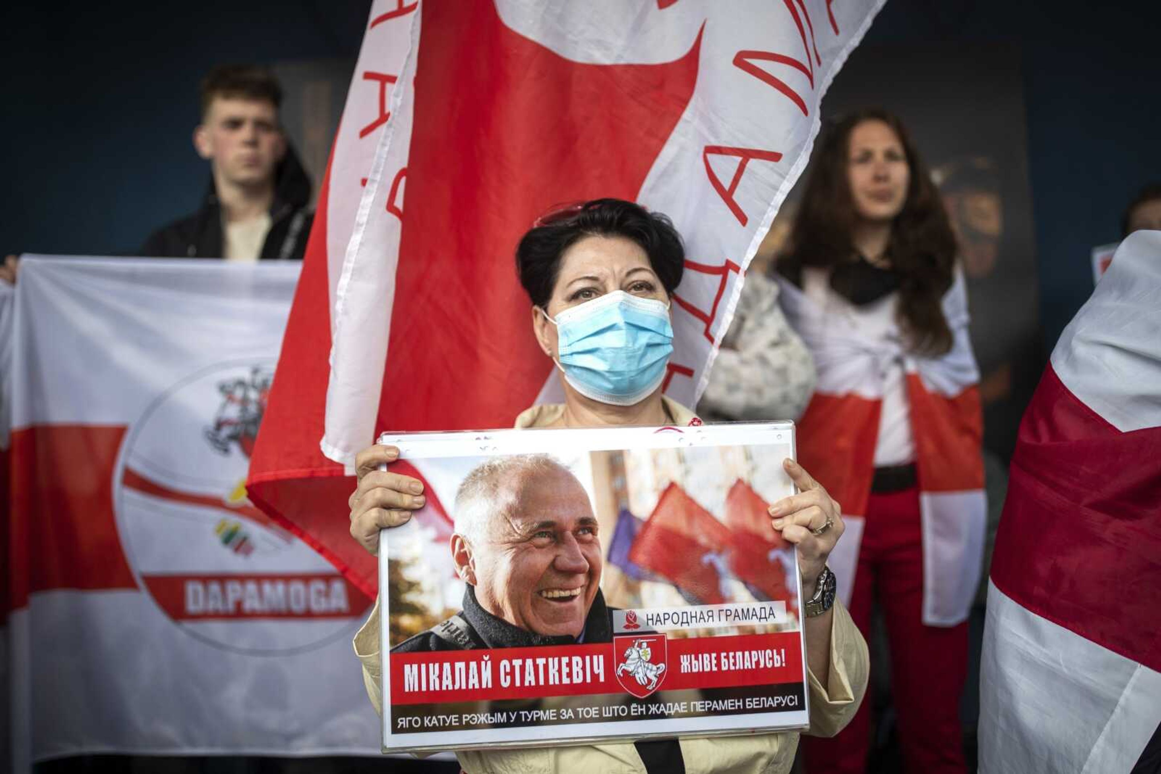 Protesters hold a poster with a portrait of opposition activist Nikolai Statkevich, who was detained while heading for a protest last year, and Old Belarusian national flags attending a rally demanding freedom for Belarus opposition activist Raman Protasevich, in front of the Belarus Embassy in Vilnius, Lithuania, Thursday, May 27, 2021. European Union nations are sketching out plans for new sanctions against Belarus that will target economic sectors close to its authoritarian president, as they seek to strike back at him for the forced diversion of a passenger jet to arrest a dissident journalist. (AP Photo/Mindaugas Kulbis)