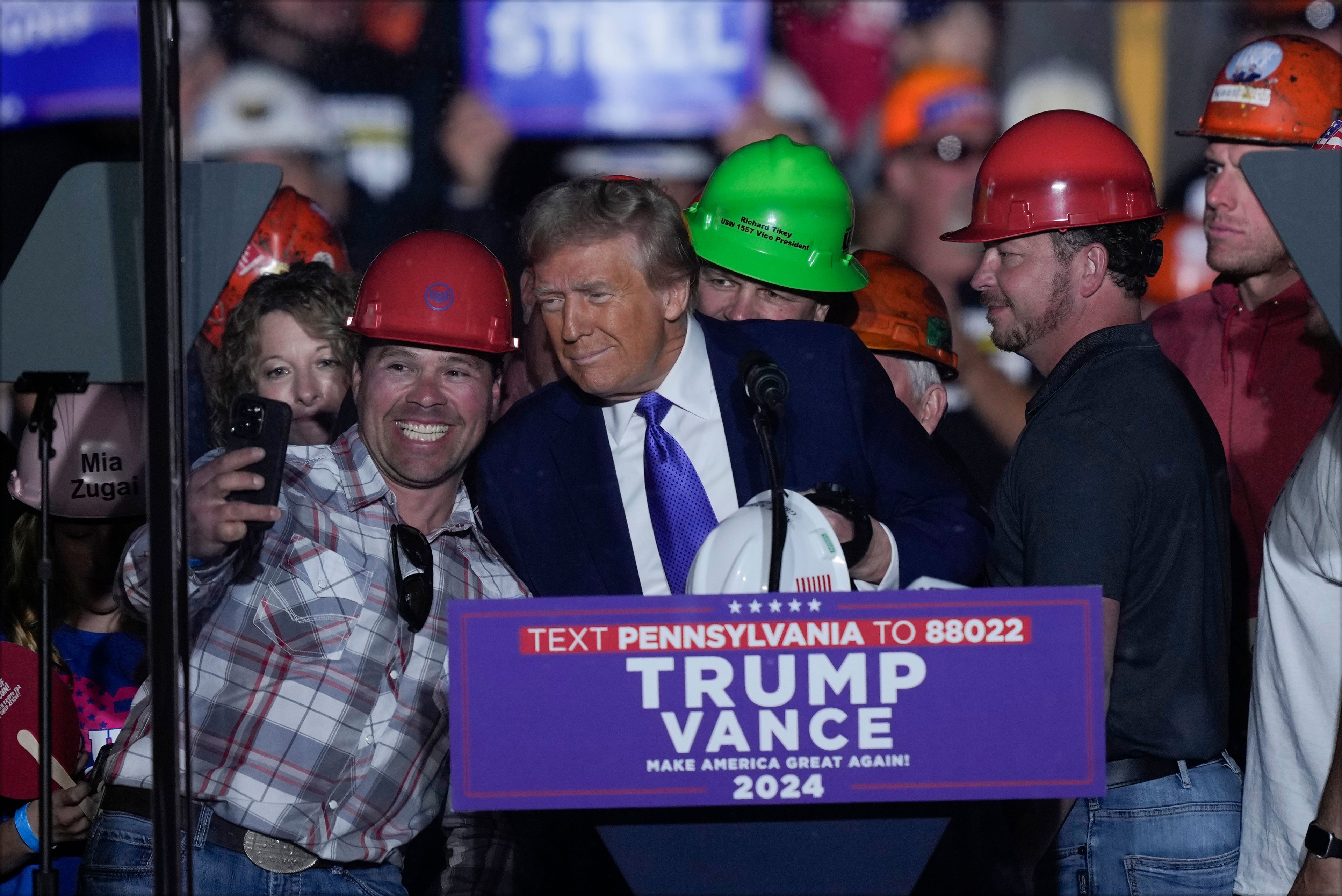 Republican presidential nominee former President Donald Trump poses for a photo as he brings steelworkers onto stage as he speaks at a campaign rally, Saturday, Oct. 19, 2024, at Arnold Palmer Regional Airport in Latrobe, Pa. (AP Photo/Matt Rourke)