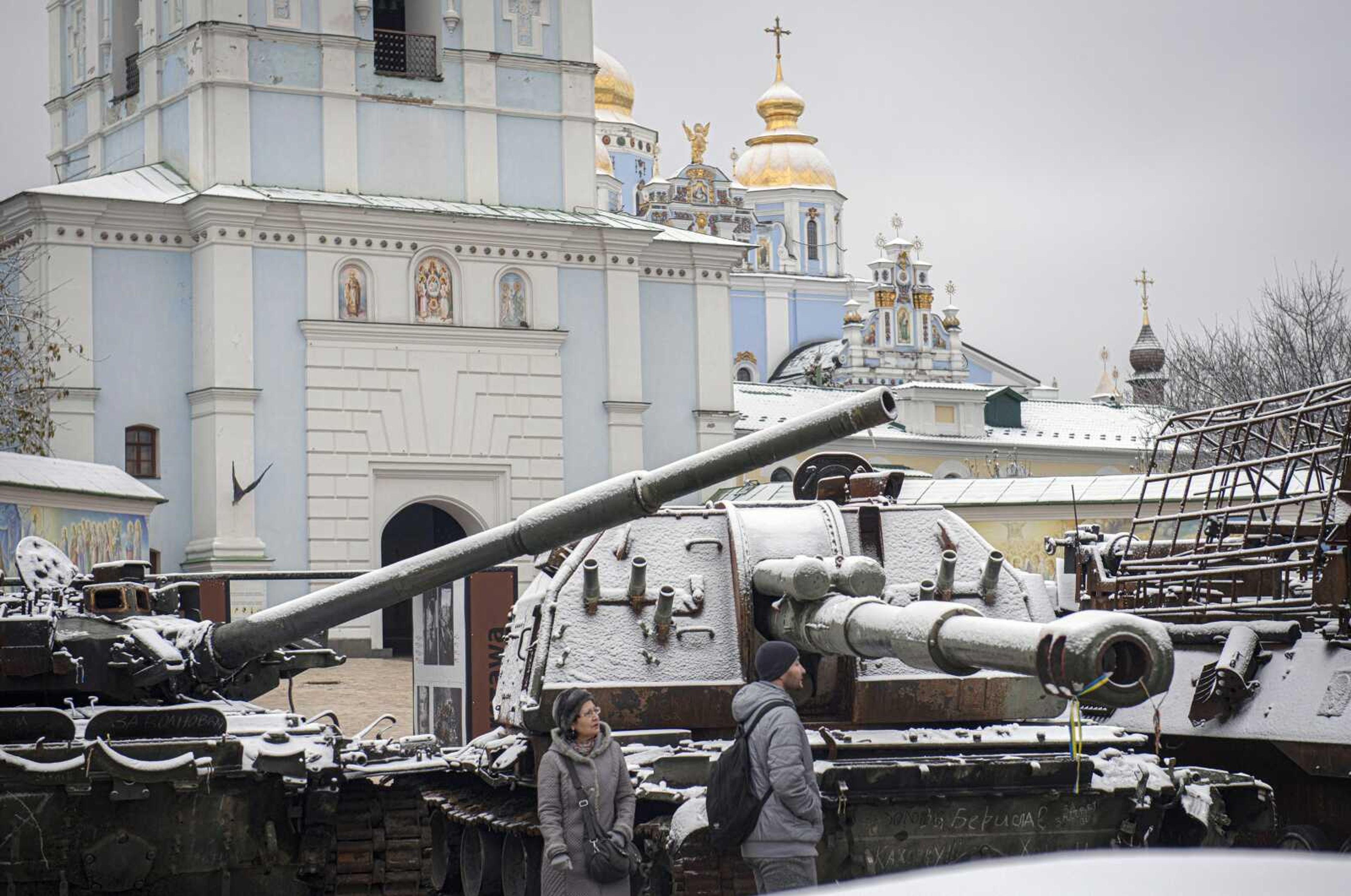 Pedestrians walk past a display of destroyed Russian tanks and armoured vehicles after snowfall Thursday in downtown Kyiv, Ukraine.