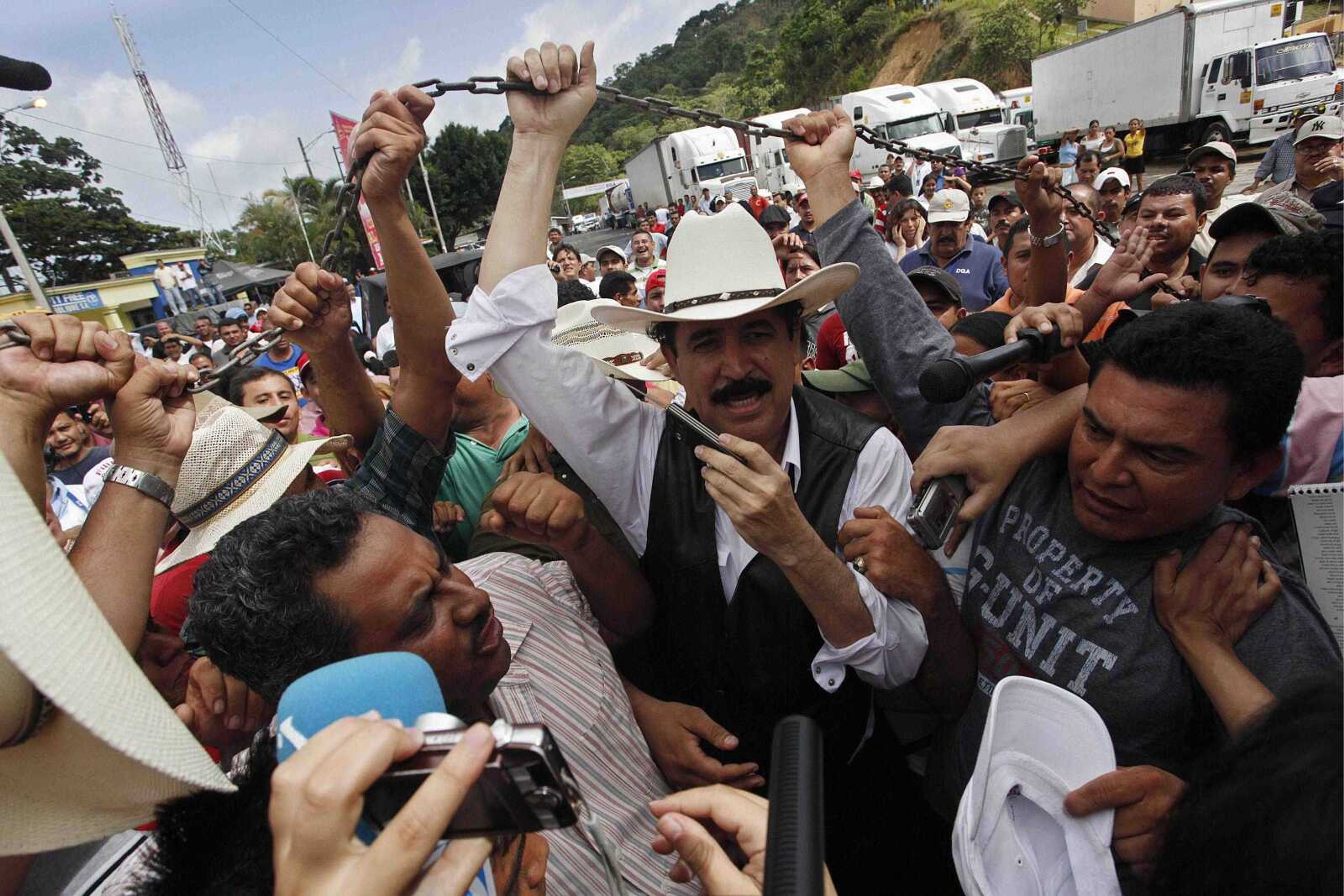 Honduras' ousted President Manuel Zelaya, surrounded by supporters and the press Friday, lifts the chain that divides the border between Nicaragua and Honduras in Las Manos, Nicaragua. (Esteban Felix ~ Associated Press)