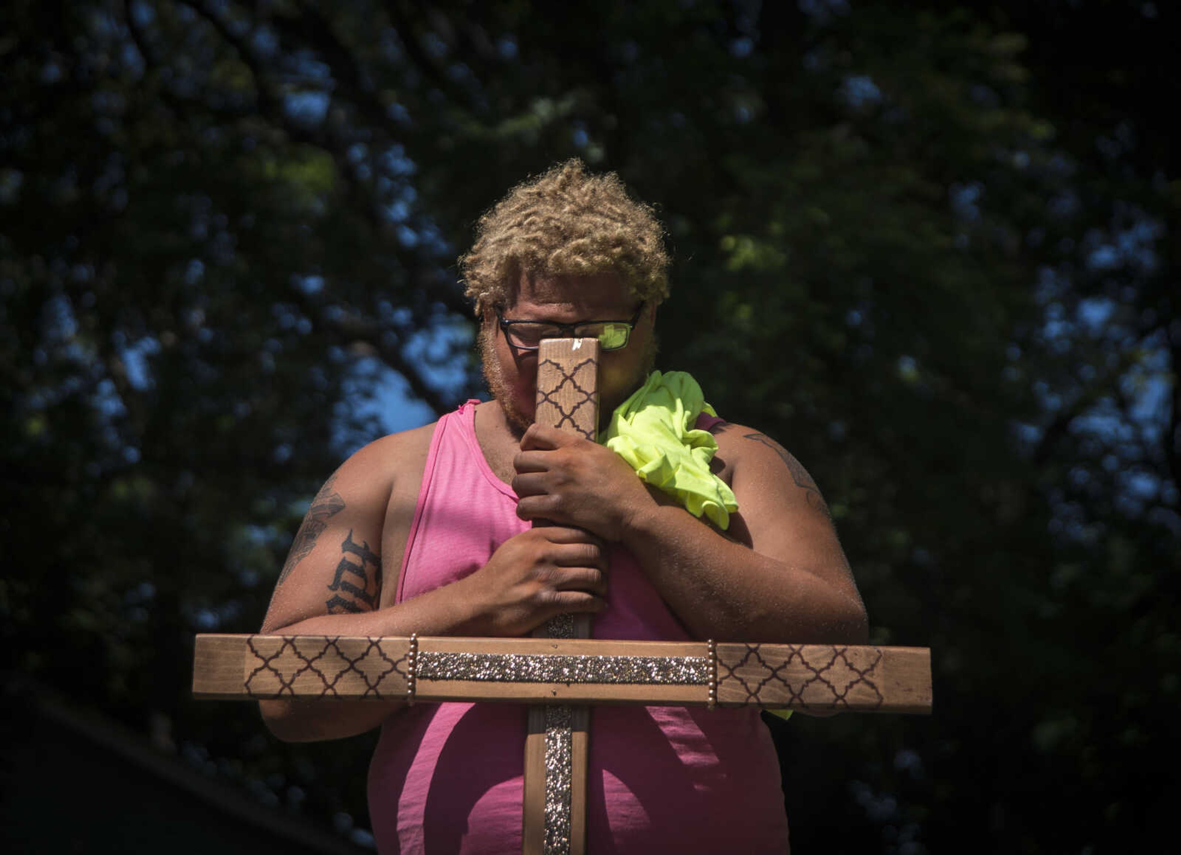 Corey Moore rests his head on a cross while a prayer is said during a Stop Needless Acts of Violence Please (SNAP) prayer march Saturday, June 10, 2017 in Cape Girardeau.