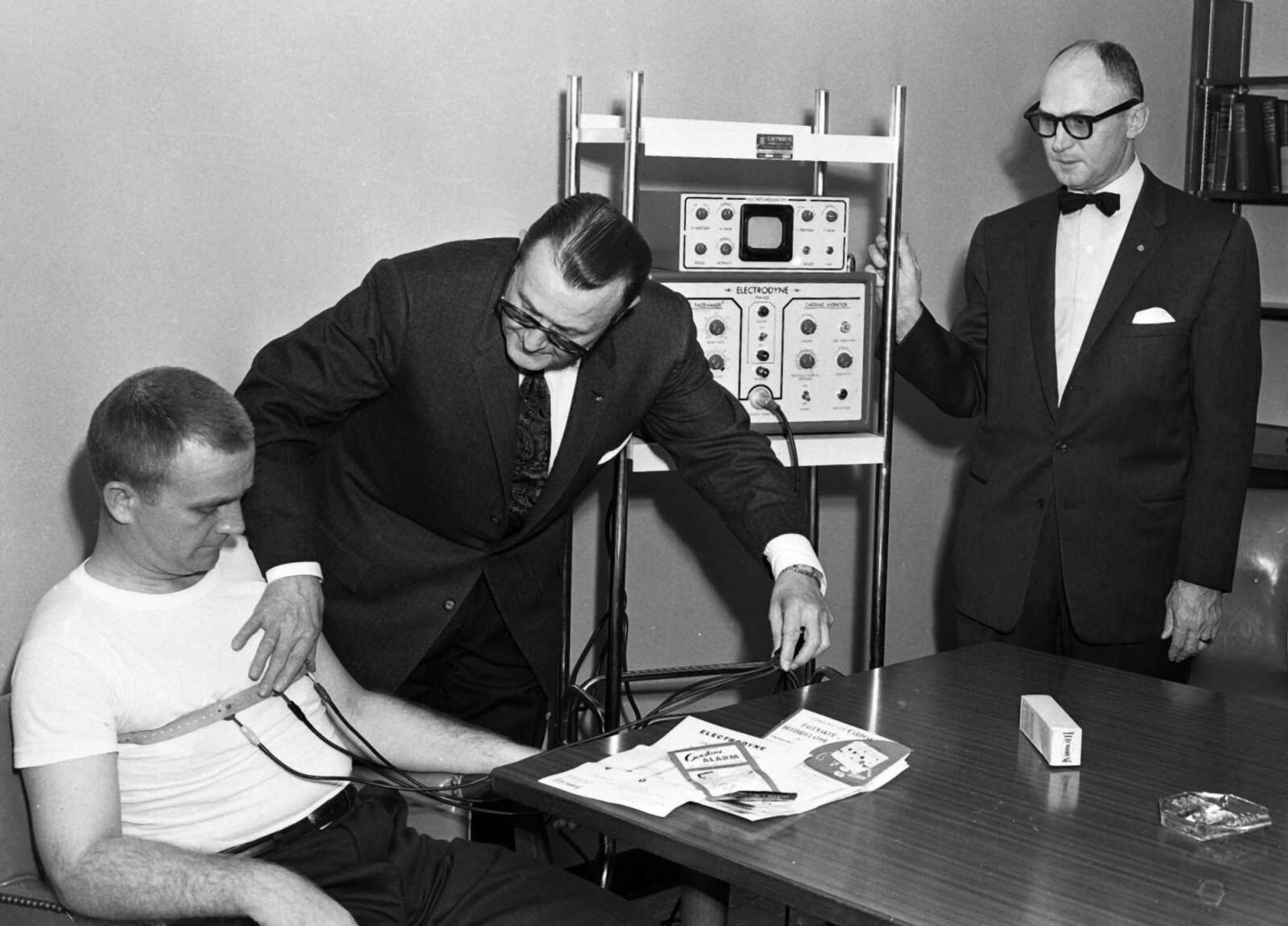 Published Saturday, Oct. 31, 1959
New equipment at Southeast Missouri Hospital. One of the first units of its kind in out-state hospitals in Missouri, is this cardiac monitor and pacemaker, which will be used extensively in surgery to detect heart changes during surgery, and also can be used in treatment of cardiac conditions. Provided as part of the community service program by the Missouri Heart Association and local heart clinic, the unit is being demonstrated here, Dr. Charles McGinty, serving as the patient, while Dr. Alter M. Estes explains the unit's operation. At the right is R.A. Fulenwider of Jackson, hospital board chairman. Other board members were present for the presentation and demonstration.