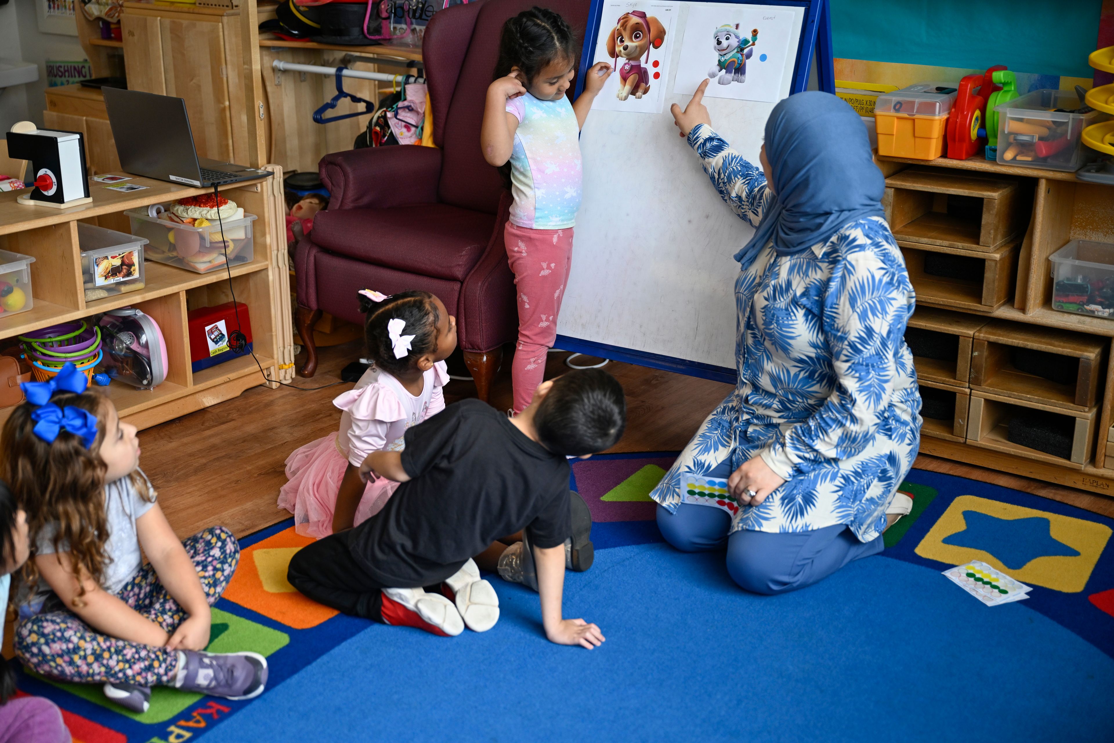 Preschool teacher Tinhinane Meziane, right, instructs to her students on how to vote the most popular character of the TV show PAW Patrol at the ACCA Child Development Center, Thursday, Sept. 19, 2024, in Annandale, Va. The students are getting foundational lessons on how to live in a democracy by allowing them to regularly vote on different things throughout the day. (AP Photo/John McDonnell)