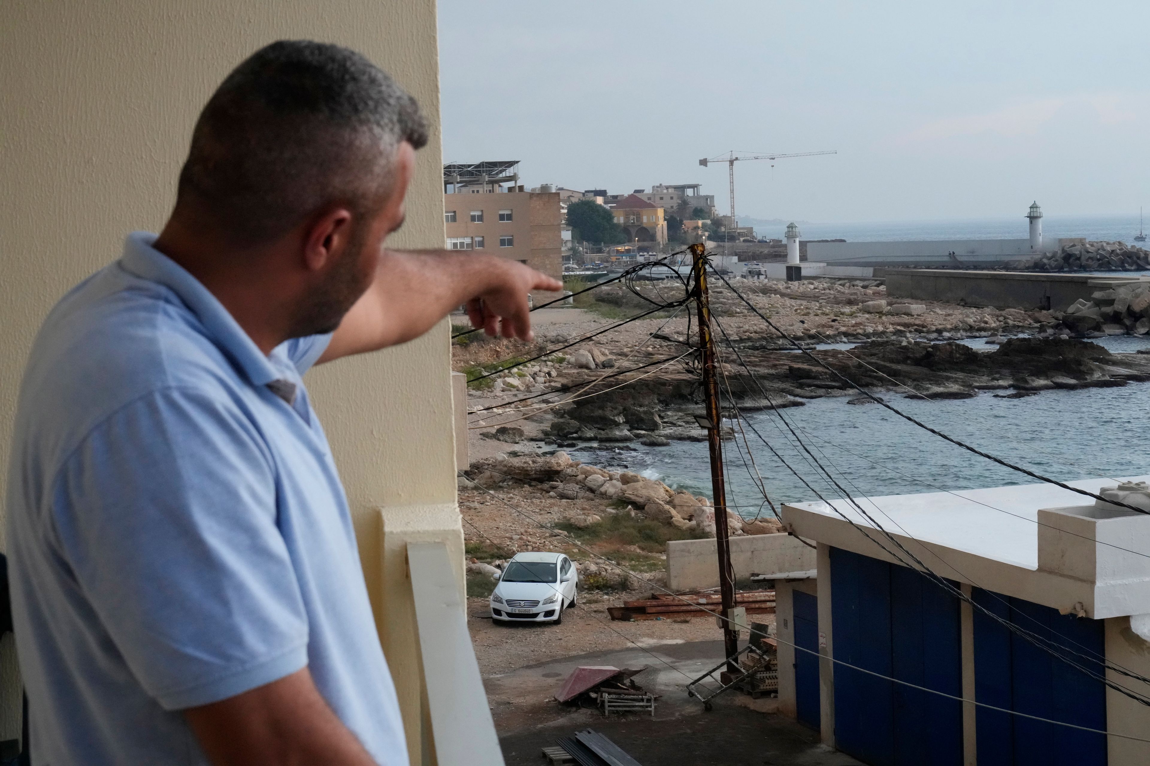 A Lebanese man points to the beach in Batroun, northern Lebanon, Saturday, Nov. 2, 2024, where Lebanese officials say a group of armed men landed on a coast north of Beirut and took away a ship captain and they're investigating whether Israel was involved. (AP Photo/Hussein Malla)