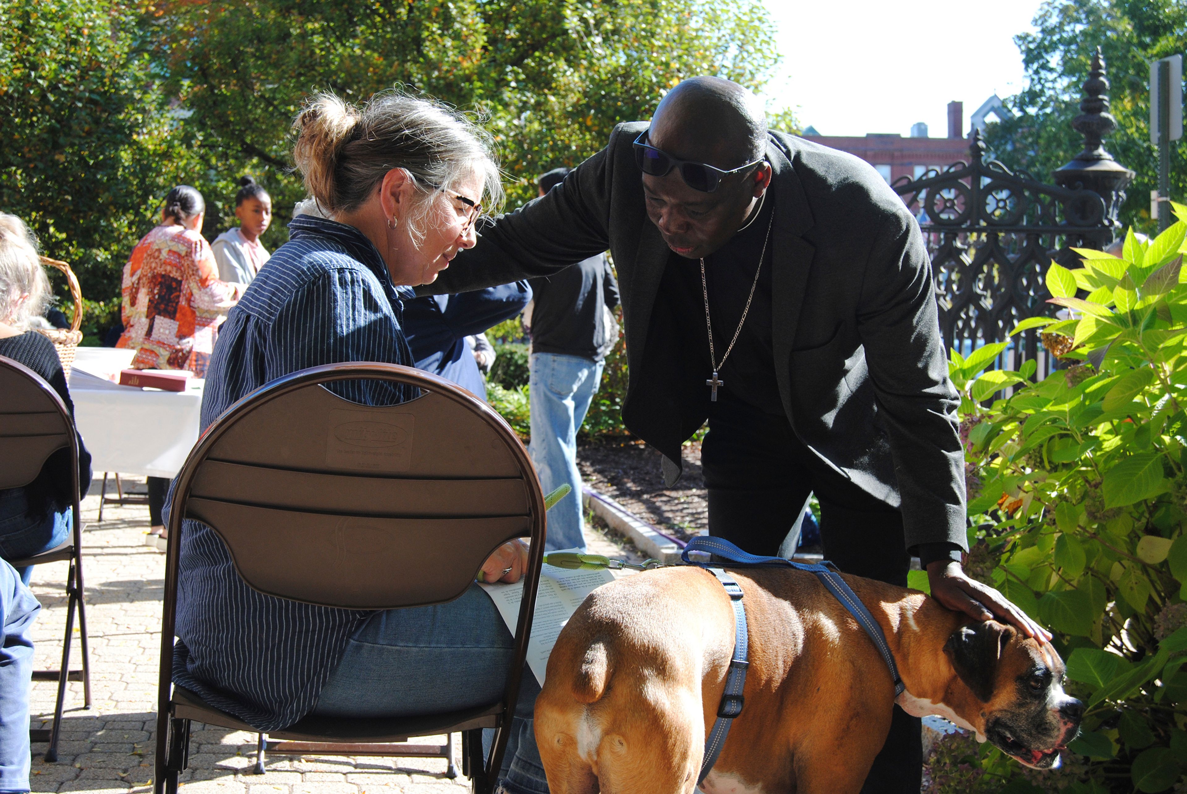 The Rev. Jean Beniste, a Haitian immigrant, blesses a dog and its owner Saturday, Oct. 5, 2024, during a Blessing of the Animals in the garden at St. Paul's Episcopal Church in Concord, N.H., where Beniste serves as rector. (G. Jeffrey MacDonald via AP)