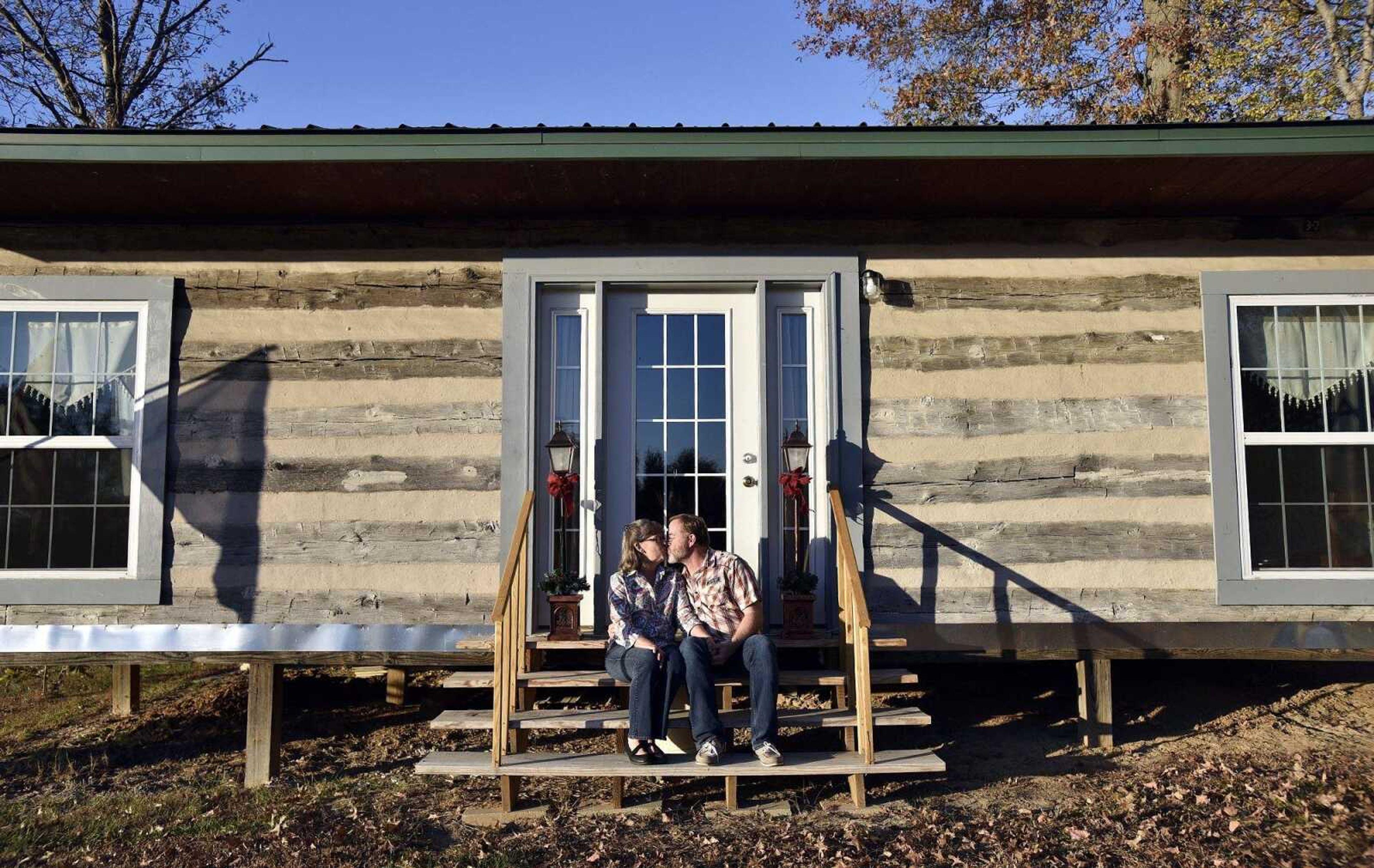 Kim and Earl Bennett sit outside the log cabin they rebuilt in Jackson. The log cabin was built by Kim's great-grandfather in 1902.