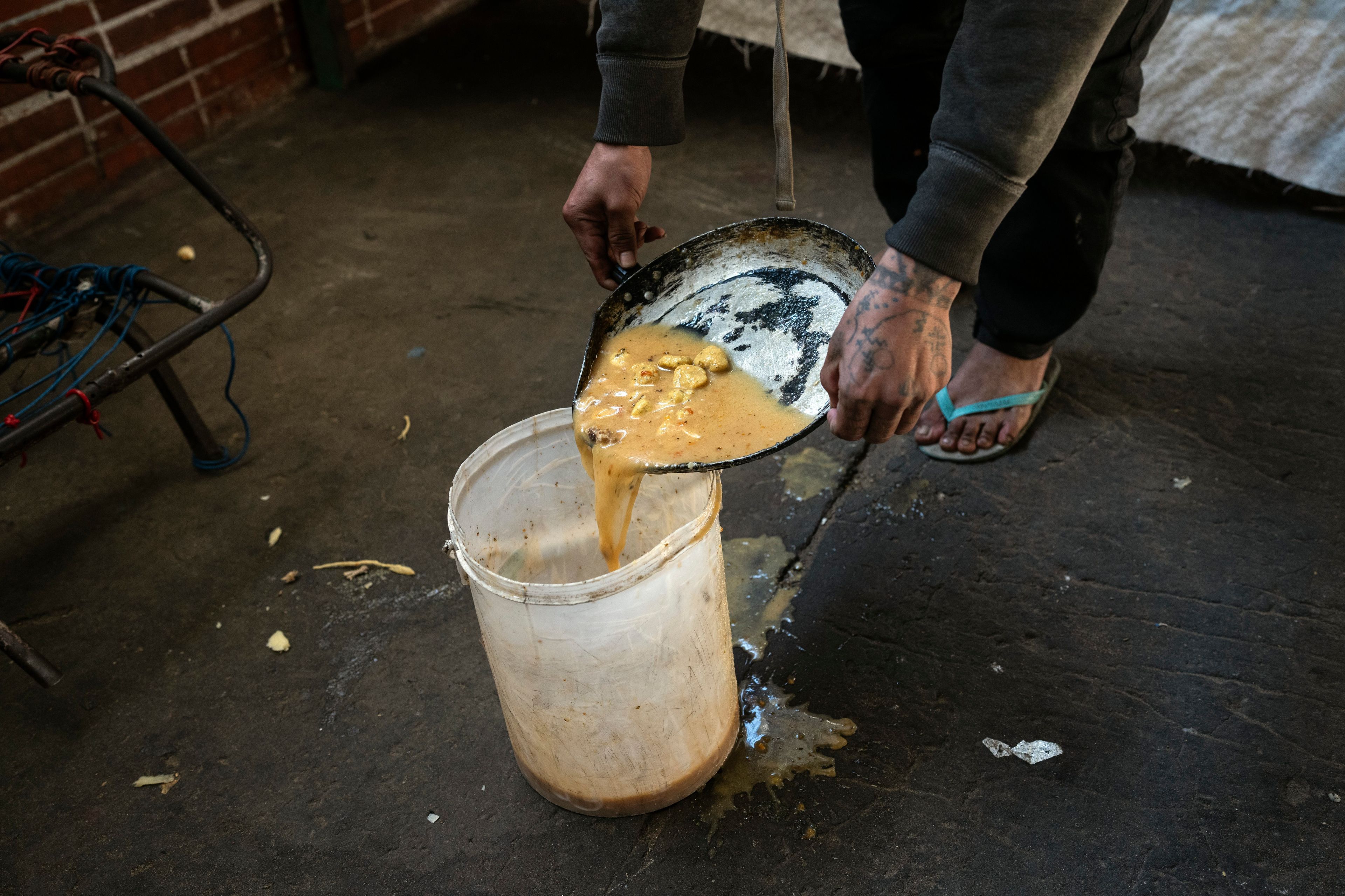 A prisoner divides up jail-provided soup known as "vori vori" at the Tacumbu prison in Asuncion, Paraguay, Wednesday, July 10, 2024. The soup, made of chicken or beef, vegetables, and corn balls stuffed with cheese, is considered the food of the poorest inmates, and those who can afford it prefer to buy other food. (AP Photo/Rodrigo Abd)