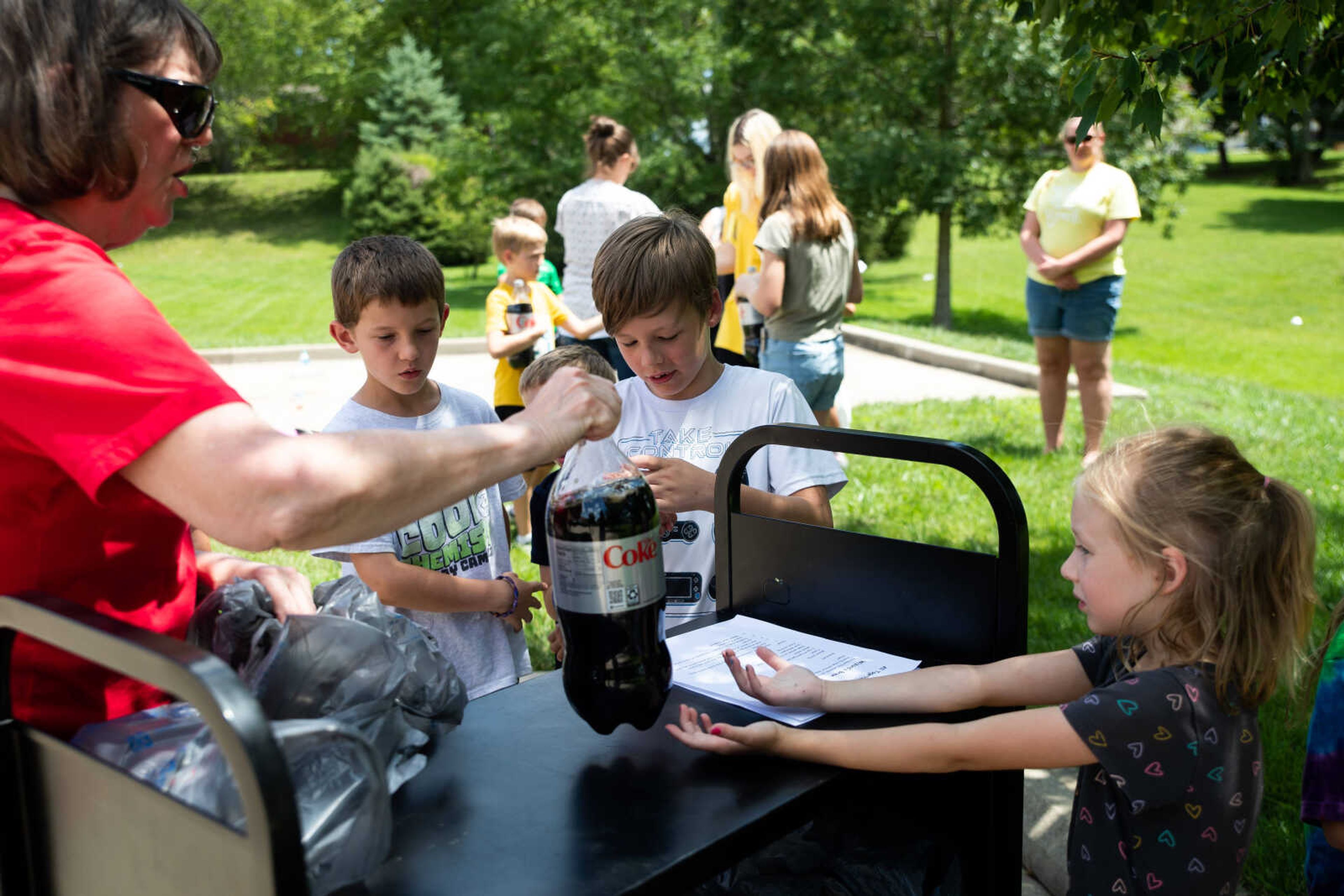 Becky Hicks hands Avery Heuring, 7, a two liter of diet coke as they prep for an experiment with Menthos.