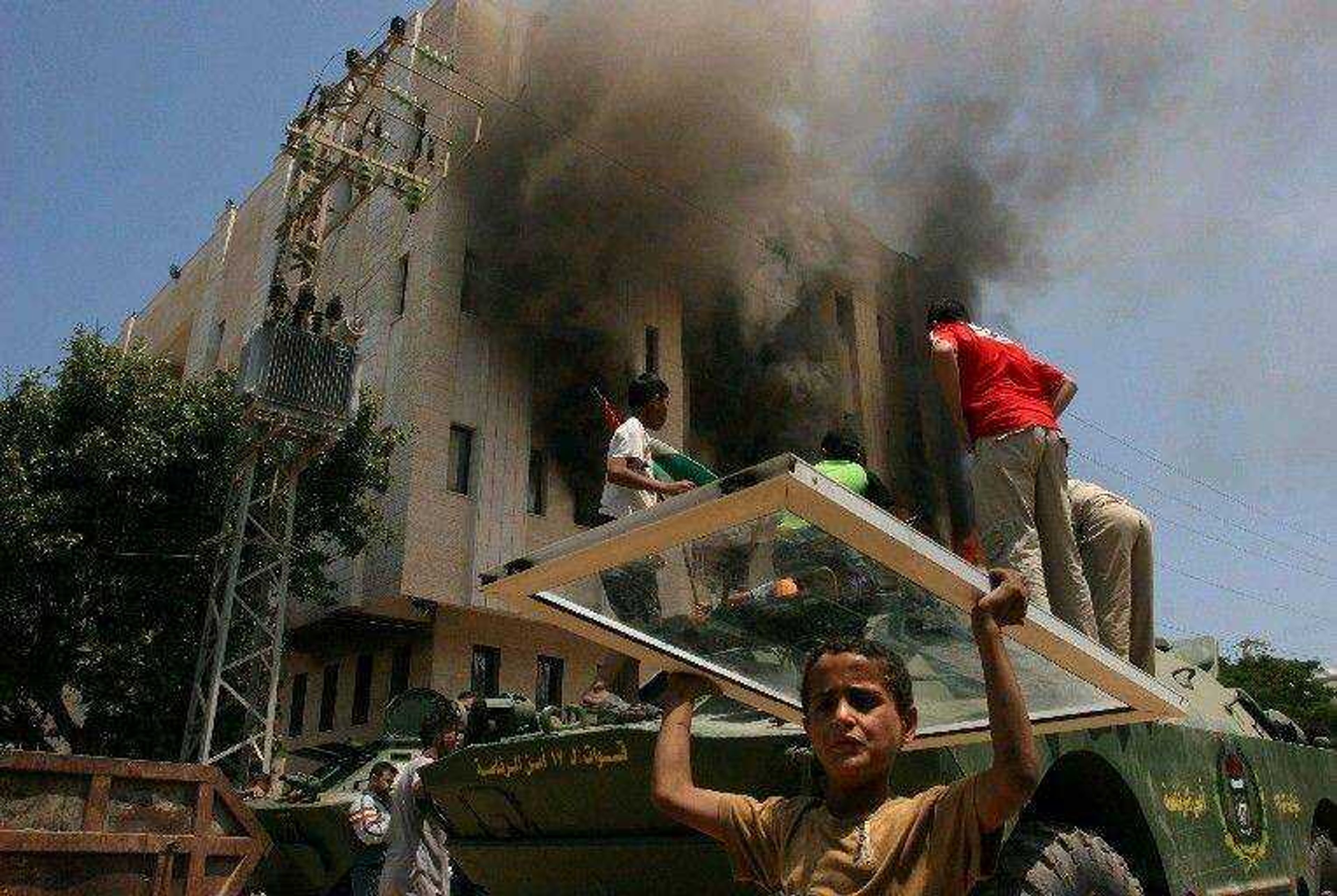 A building burned Friday as a Palestinian youth carried a window he looted from a building in Palestinian President Mahmoud Abbas' compound after it was taken over by Hamas militants in fighting in Gaza City. The Palestinian territories have essentially been split into two parts. Gaza is now under the control of Hamas, an Islamist movement with close ties to Syria and Iran. The West Bank, home to most of the Palestinian population, is dominated by the more moderate Fatah, which has ties to Israel and the West. (WISSAM NASSAR ~ MaanImages)