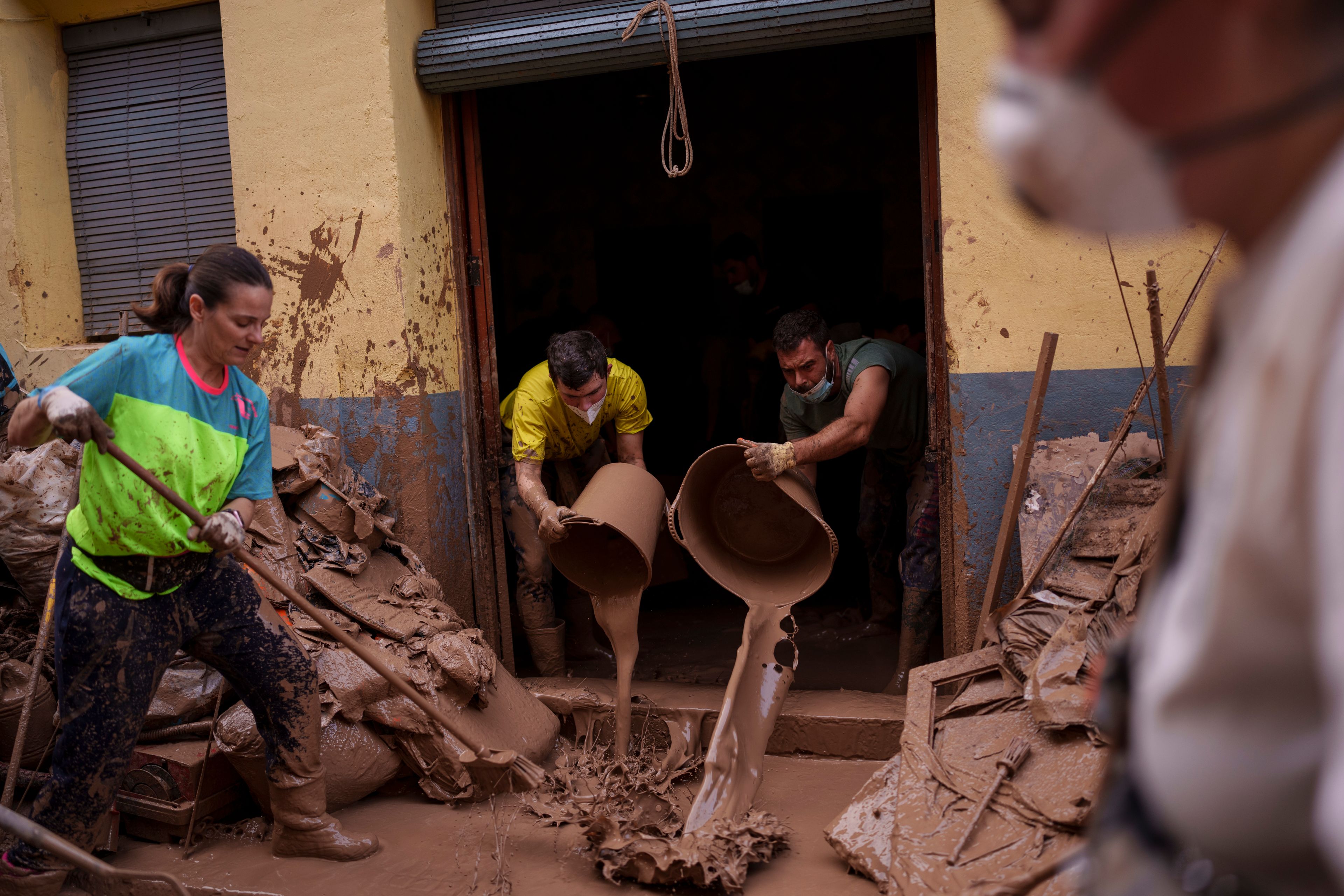 People clean mud from a house affected by floods, in Algemesi, Spain, Sunday, Nov. 3, 2024. (AP Photo/Manu Fernandez)