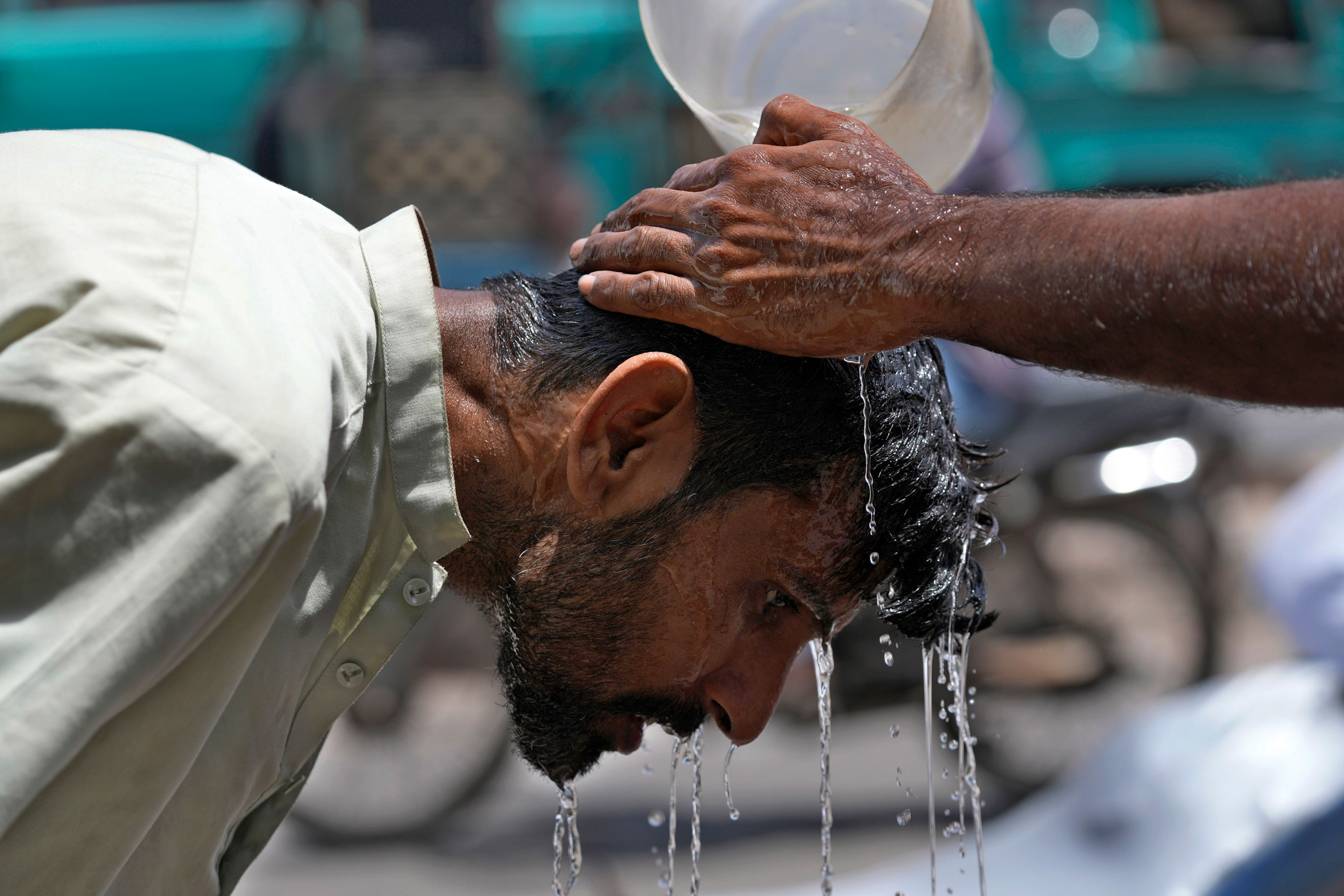 FILE - A volunteer pours water to cool a man off during a hot day in Karachi, Pakistan, May 21, 2024. (AP Photo/Fareed Khan, File)