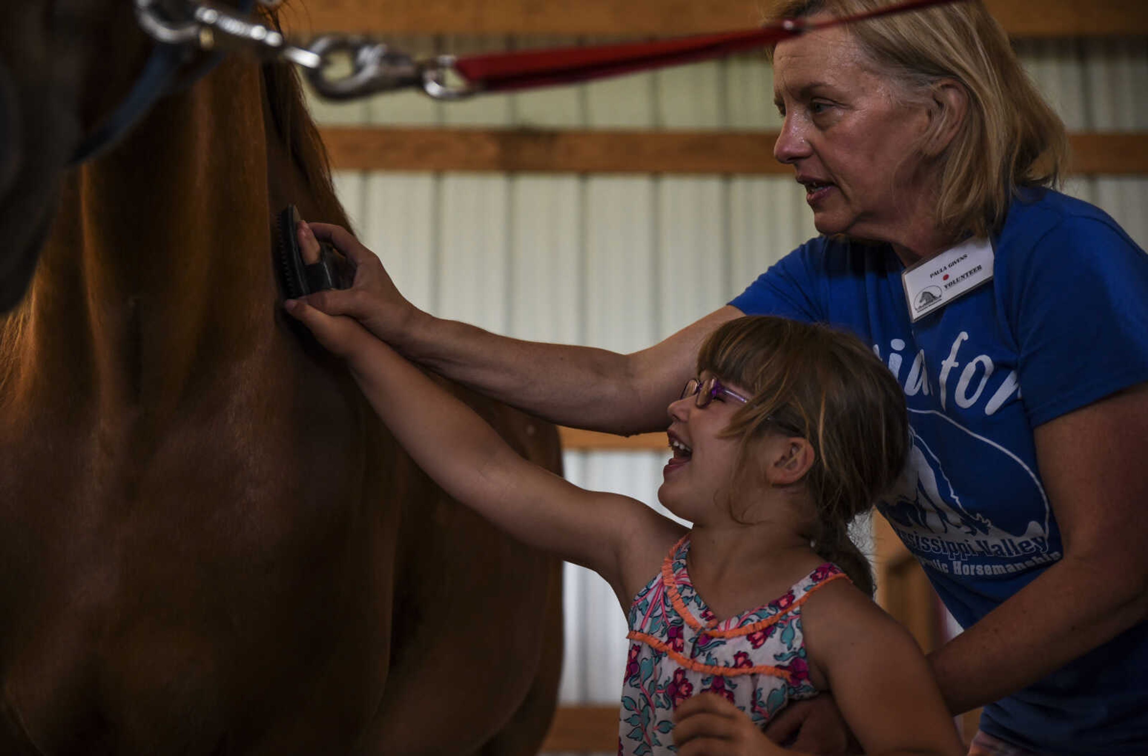 Lindyn Davenport brushes Ranger, 15, as Paula Givens, helps guide her hand during a summer camp session at Mississippi Valley Therapeutic Horsemanship Friday, June 8, 2018 in Oak Ridge.