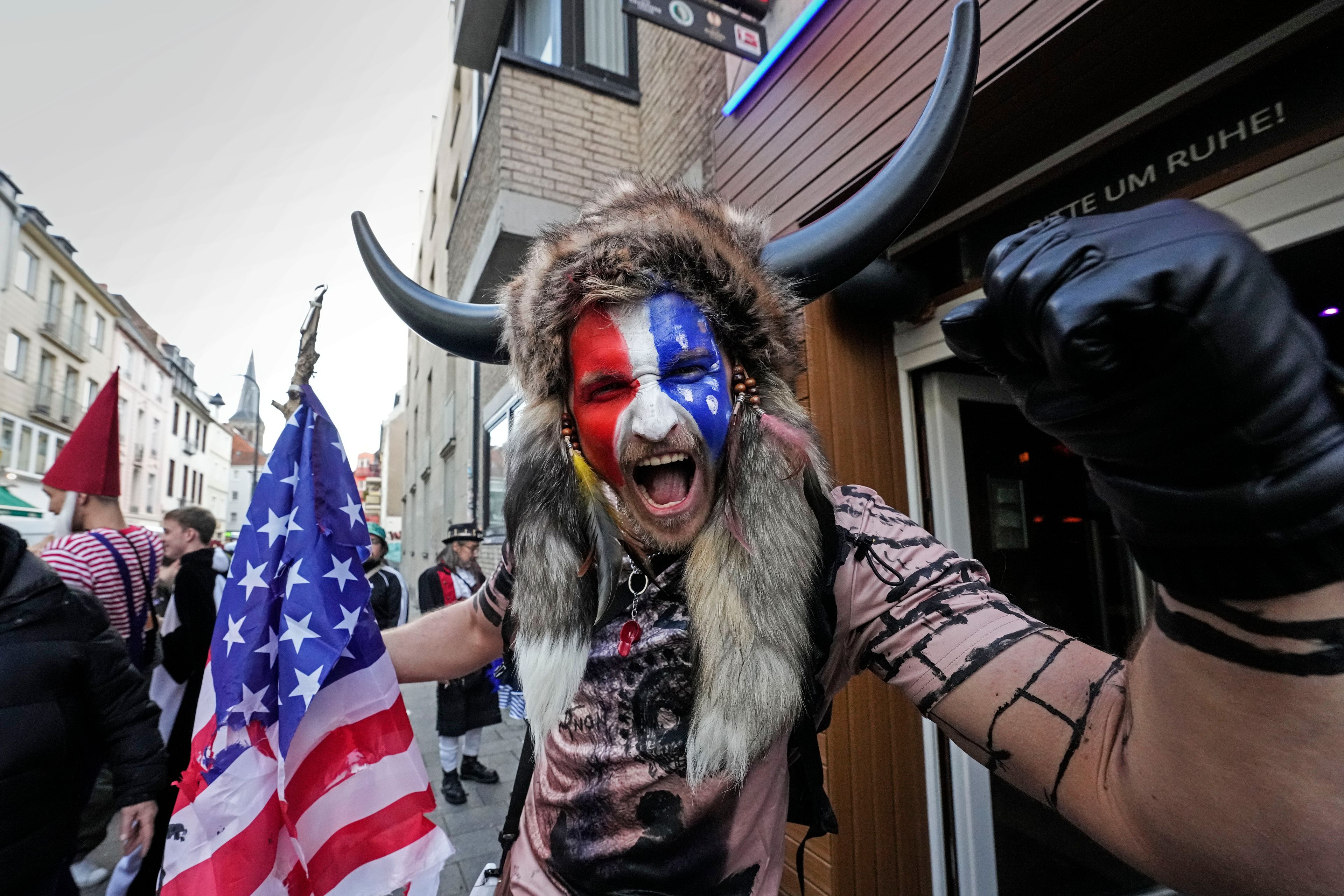 A carnival reveller in a QAnon Shaman - Jacob Chansley costume poses in the Cologne city center while tens of thousands of carnival fools take to the streets of Cologne, Germany, on Monday, November 11, 2024, heralding the official start of the carnival season. (AP Photo/Martin Meissner)