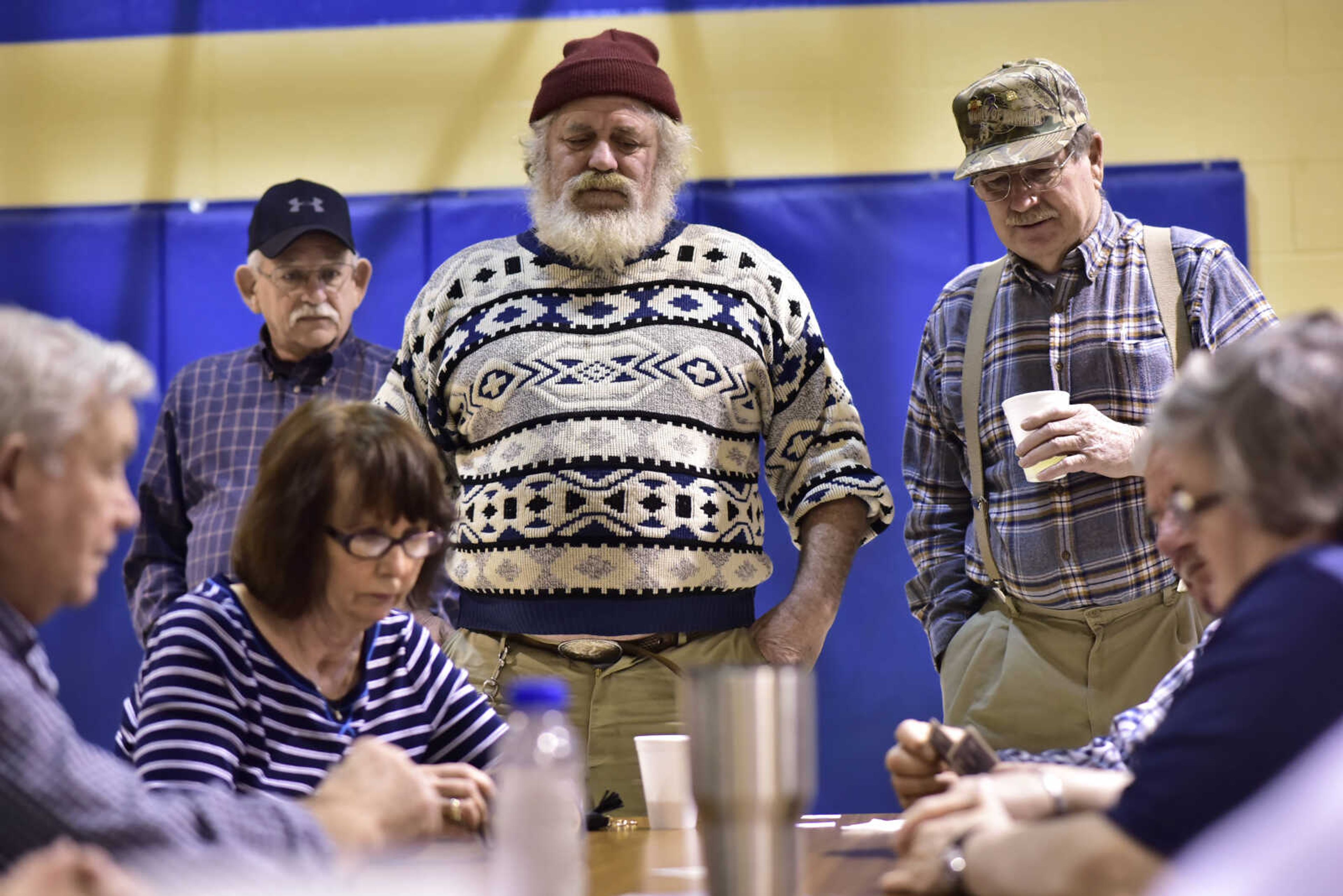 From left, Jerry Heuring, Phil Ridica and Ralph Enderle stand over a table to watch the end of a Euchre game Jan. 21, 2018, during a tournament at the Saint Ambrose Parish Center in Chaffee, Missouri.