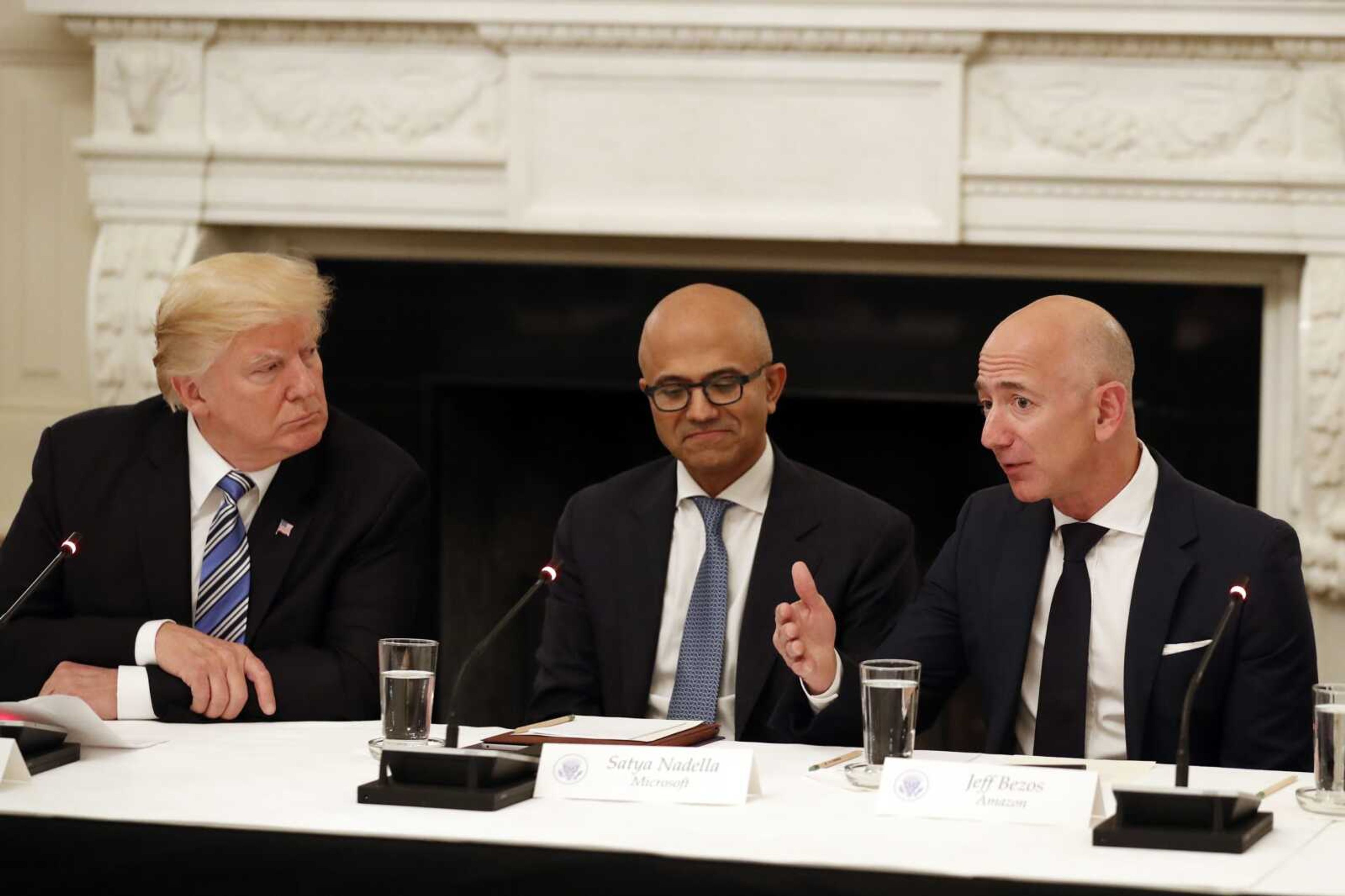 President Donald Trump, left, and Satya Nadella, chief executive officer of Microsoft, center, listen as Jeff Bezos, chief executive officer of Amazon, speaks during a 2017 American Technology Council roundtable in the State Dinning Room of the White House in Washington.