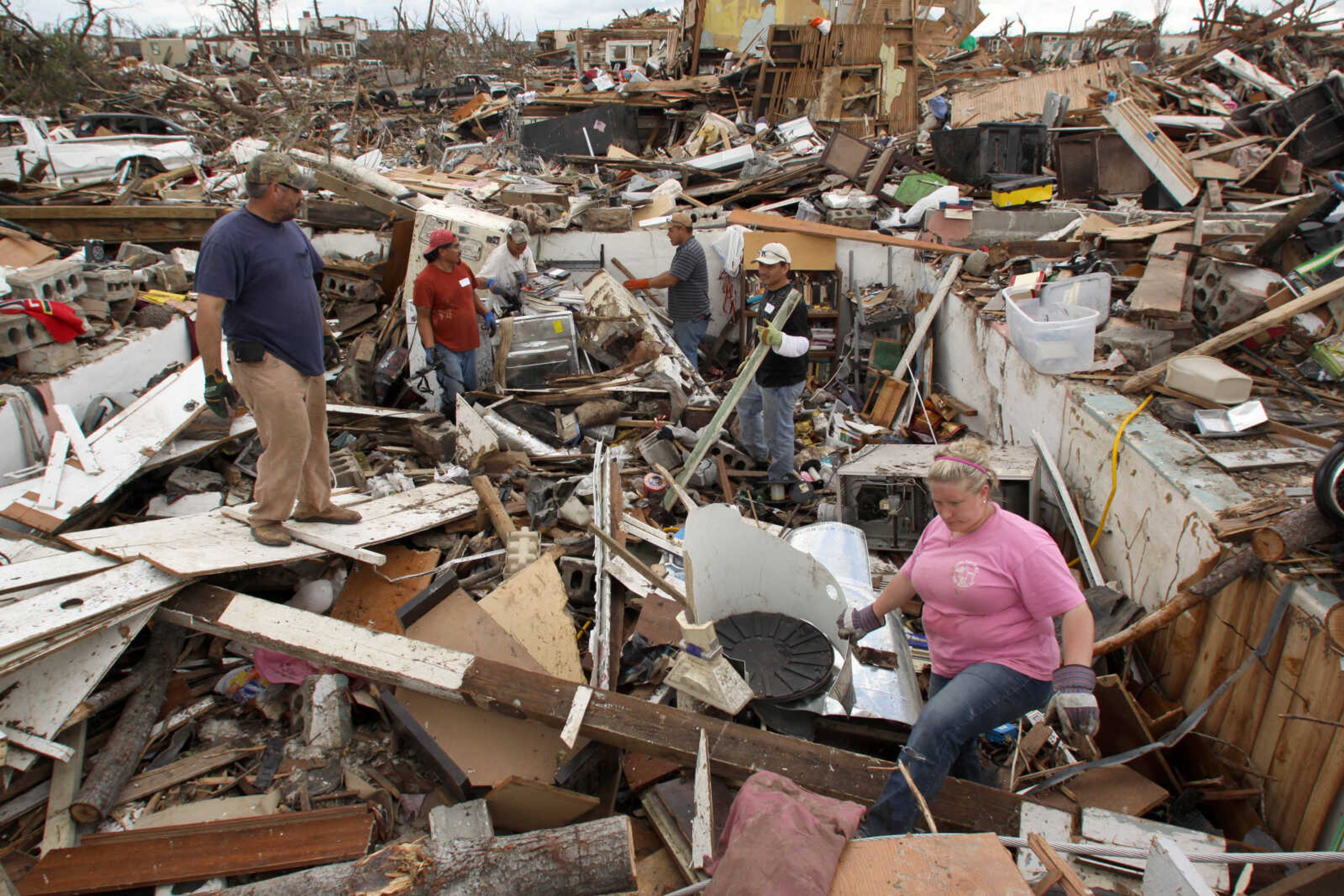 A crew of volunteers from Springfield, Ark., help Ashley Hailey search for items in the wreckage of her home's basement in Joplin, Mo., Wednesday, May 25, 2011. At least 123 people were killed and hundreds more injured when a tornado cut a destructive path through Joplin on Sunday evening. Hailey and her husband were not at home when the tornado struck. (AP Photo/Mark Schiefelbein)