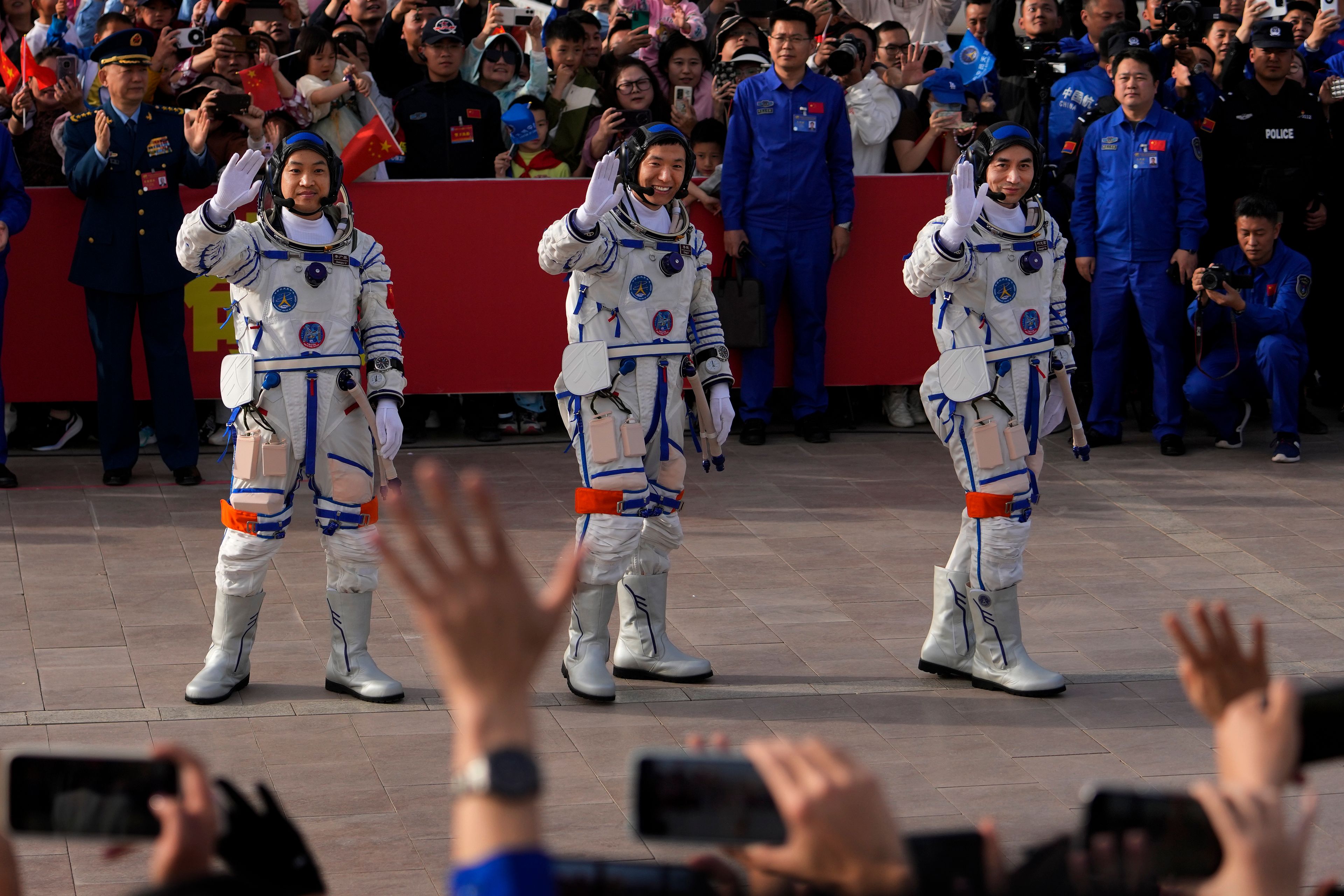 FILE -Chinese astronauts for the Shenzhou-18 mission, from right, Ye Guangfu, Li Cong, and Li Guangsu wave as they attend a send-off ceremony for their manned space mission at the Jiuquan Satellite Launch Center in northwestern China, April 25, 2024. (AP Photo/Andy Wong, File)