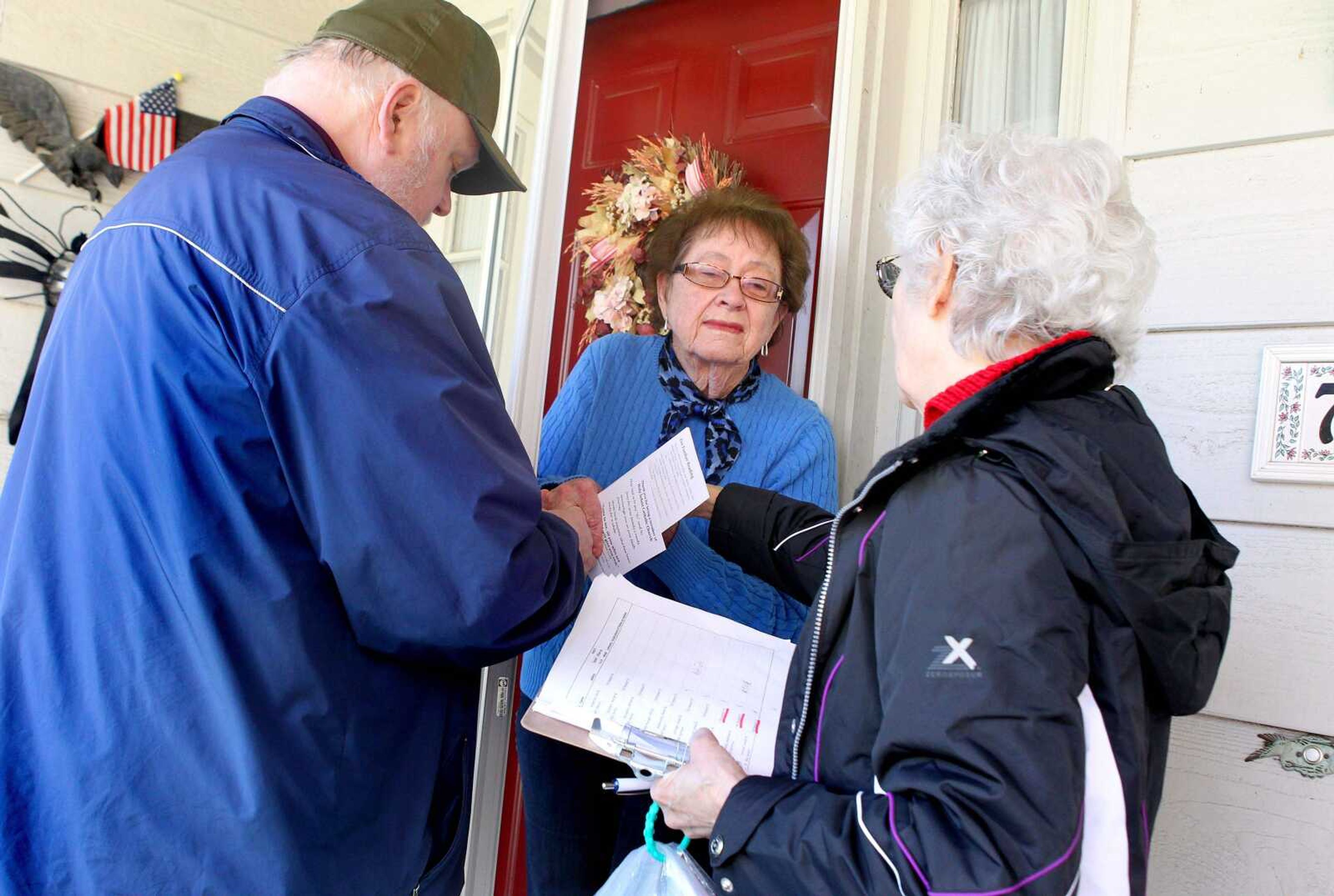 Jim Wedick, left, and Marty Scrima, right, pray with Shirley Huesgen at her doorstep April 20 in the New Ballwin Estates subdivision in Ellisville, Mo. Wedick and Scrima are members of the Holy Infant Catholic Church evangelization team. They go door to door to re-welcome registered members to restart an active membership at the church and take suggestions on how to make worship better. (Christian Gooden ~ St. Louis Post-Dispatch)