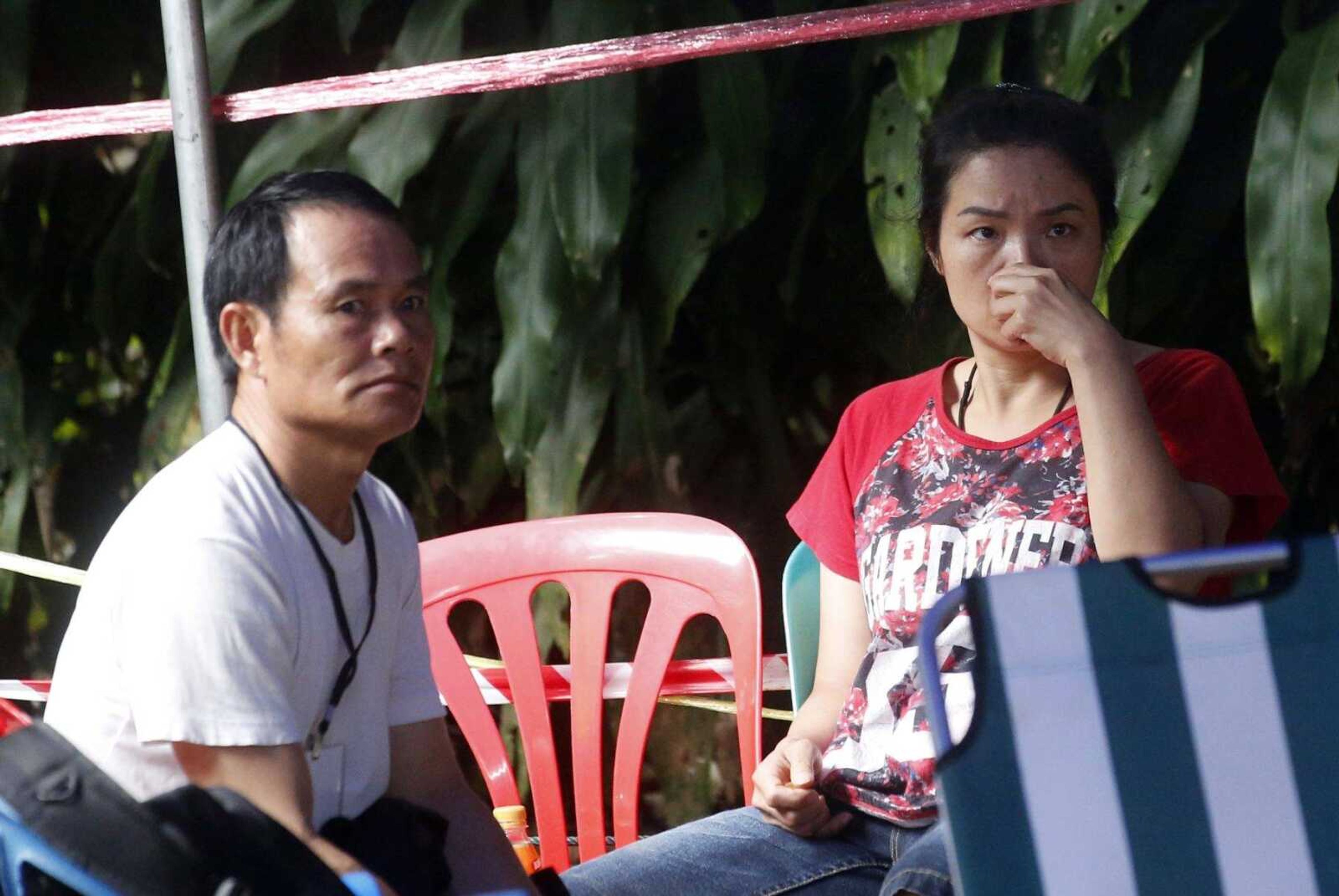 Family members sit Friday in a tent near a cave where 12 boys and their soccer coach have been trapped since June 23 in northern Thailand. Thai authorities are racing to pump out water from the flooded cave before more rains are forecast to hit the region.