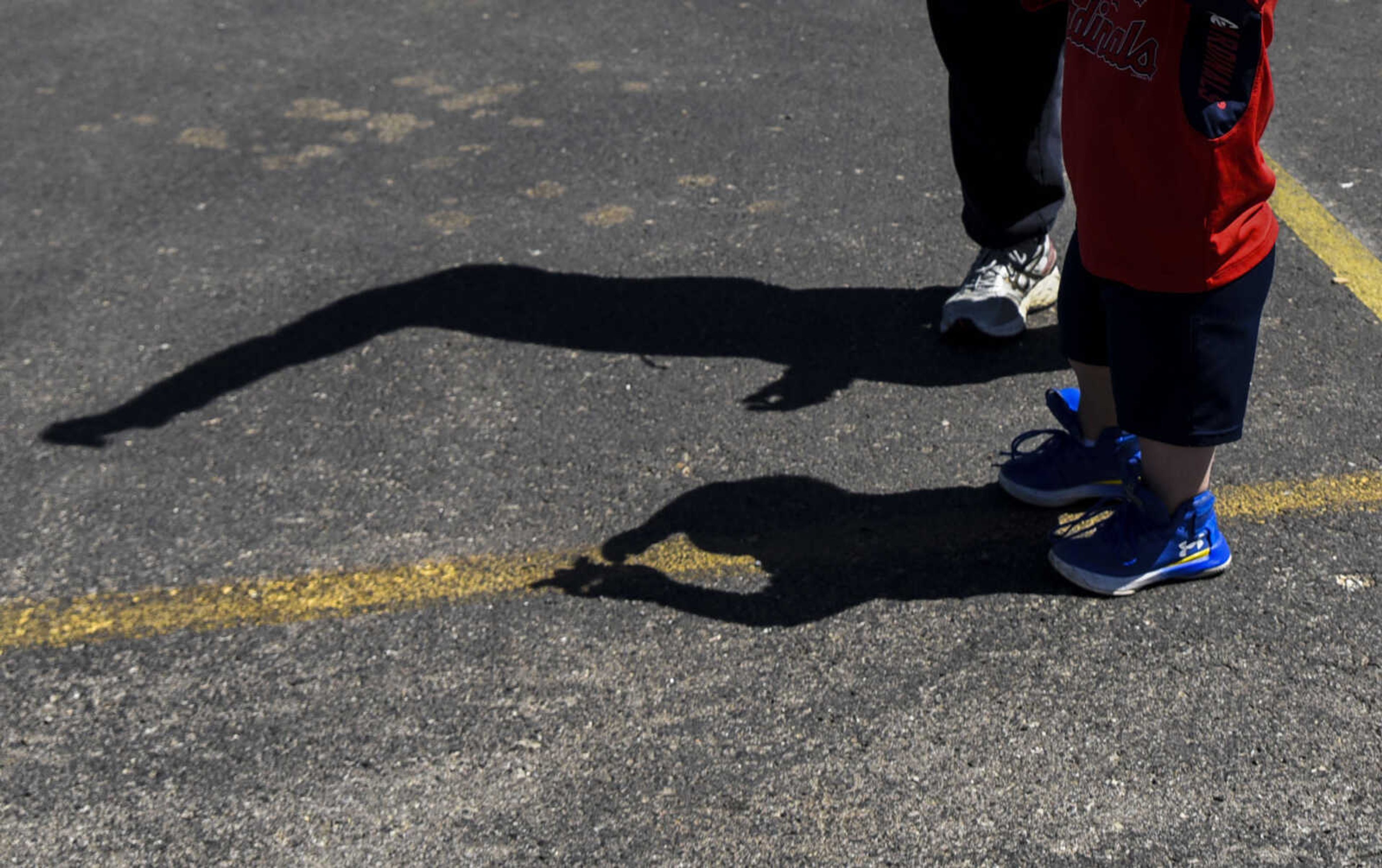 The shadows of Izaac Pursley, front, and Coach Jerry Golden, back, are seen as they fly a kite in the parking lot of North Elementary School April 20, 2018, in Jackson.