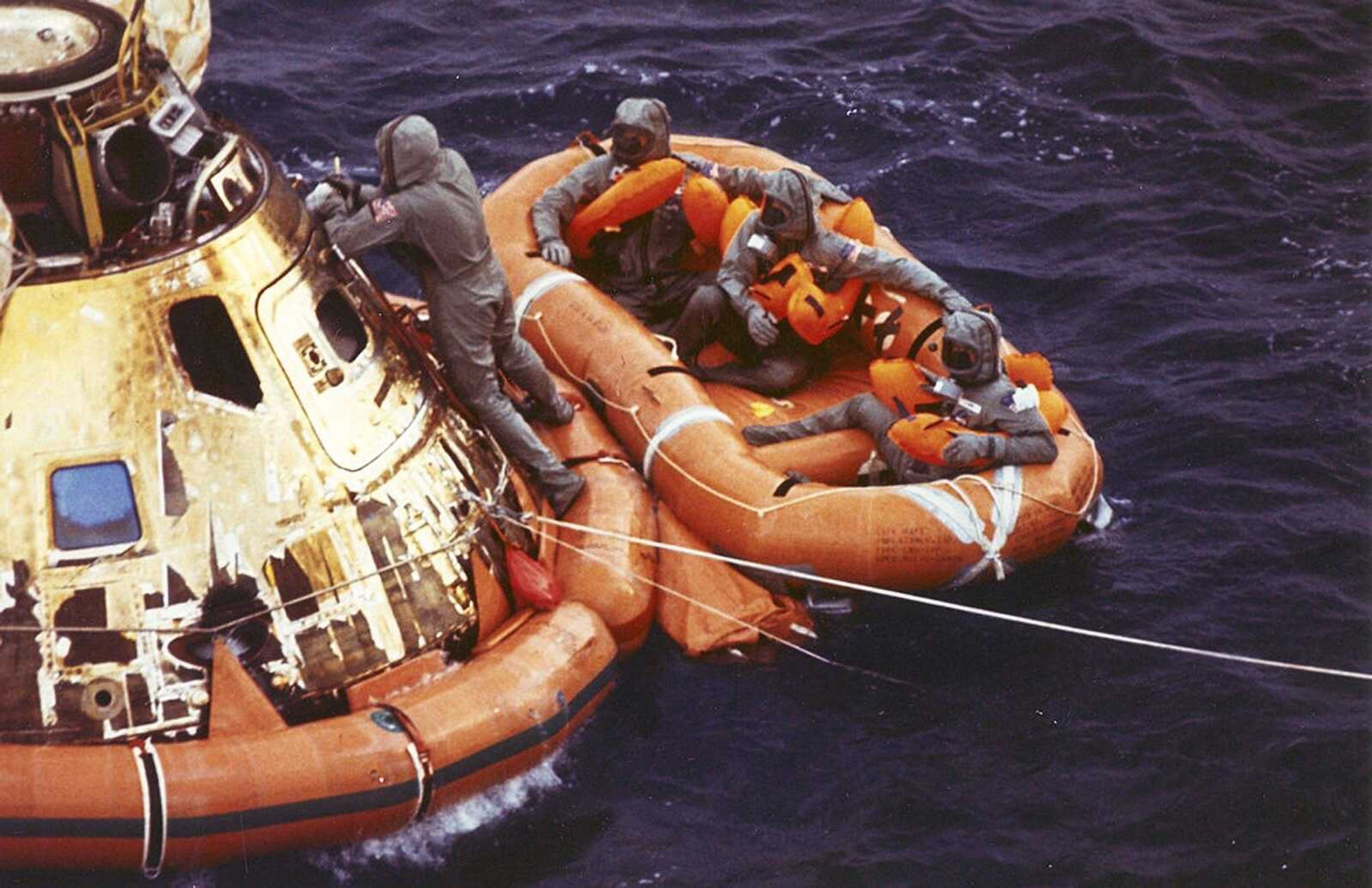 FILE - In this July 24, 1969 photo from the U.S. Navy, Lt. Clancy Hatleberg closes the Apollo 11 spacecraft hatch as astronauts Neil Armstrong, Michael Collins, and Buzz Aldrin, Jr., await helicopter pickup from their life raft after splashdown in the Pacific Ocean, 900 miles southwest of Hawaii, returning to Earth from a successful lunar landing mission. His mission was to decontaminate the astronauts and their command module, Columbia, immediately following splashdown. (Milt Putnam/U.S. Navy via AP)