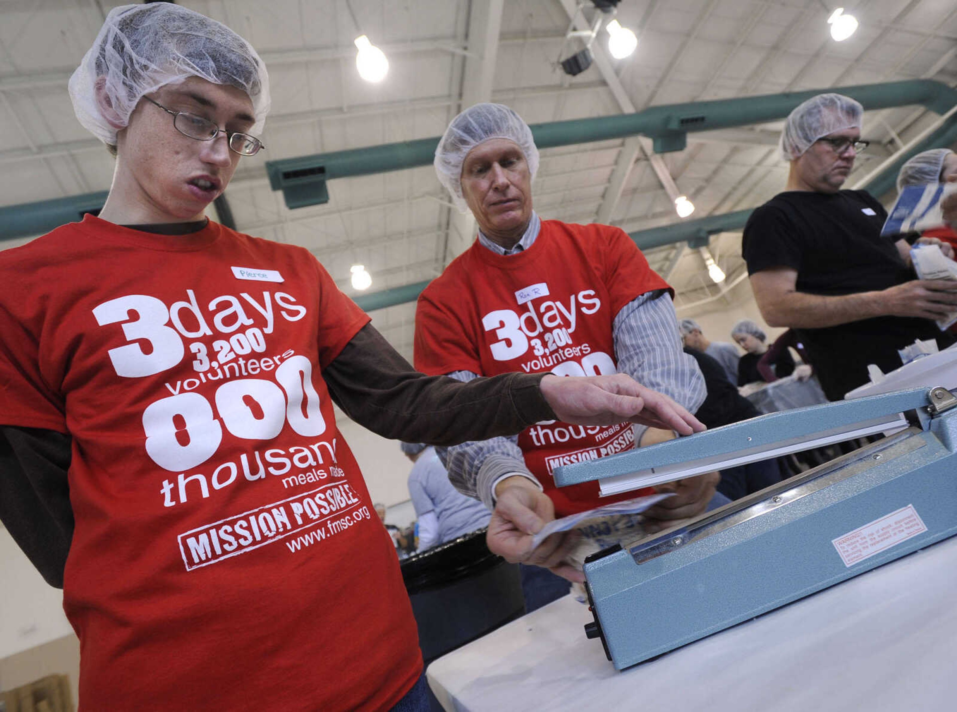 Pierce Robertson, left, and Ron Robertson operate the sealer on the MannaPack rice line at the Feed My Starving Children MobilePack event Sunday, Dec. 7, 2014 at the Osage Centre in Cape Girardeau.