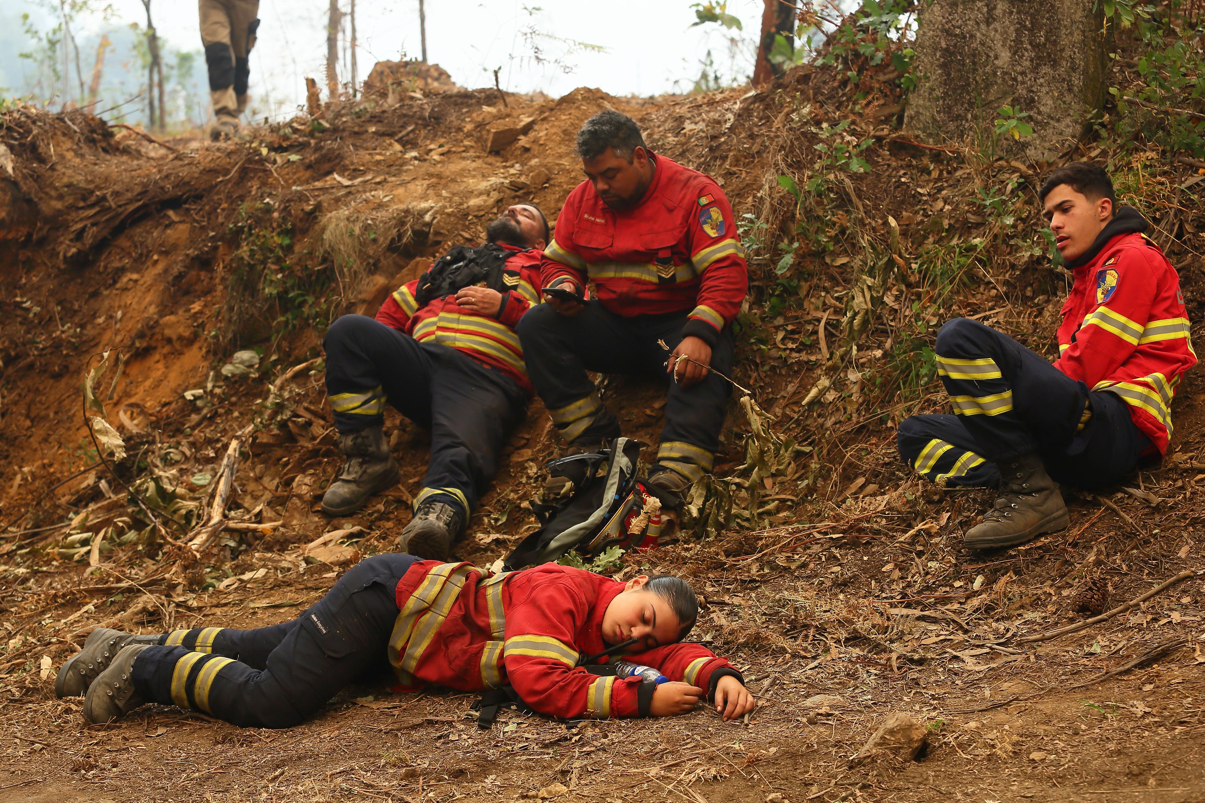 Firefighters rest during a break battling against fires on the outskirts of Sever do Vouga, a town in northern Portugal that has been surrounded by forest fires for several days, Wednesday, Sept. 18, 2024. (AP Photo/Bruno Fonseca)