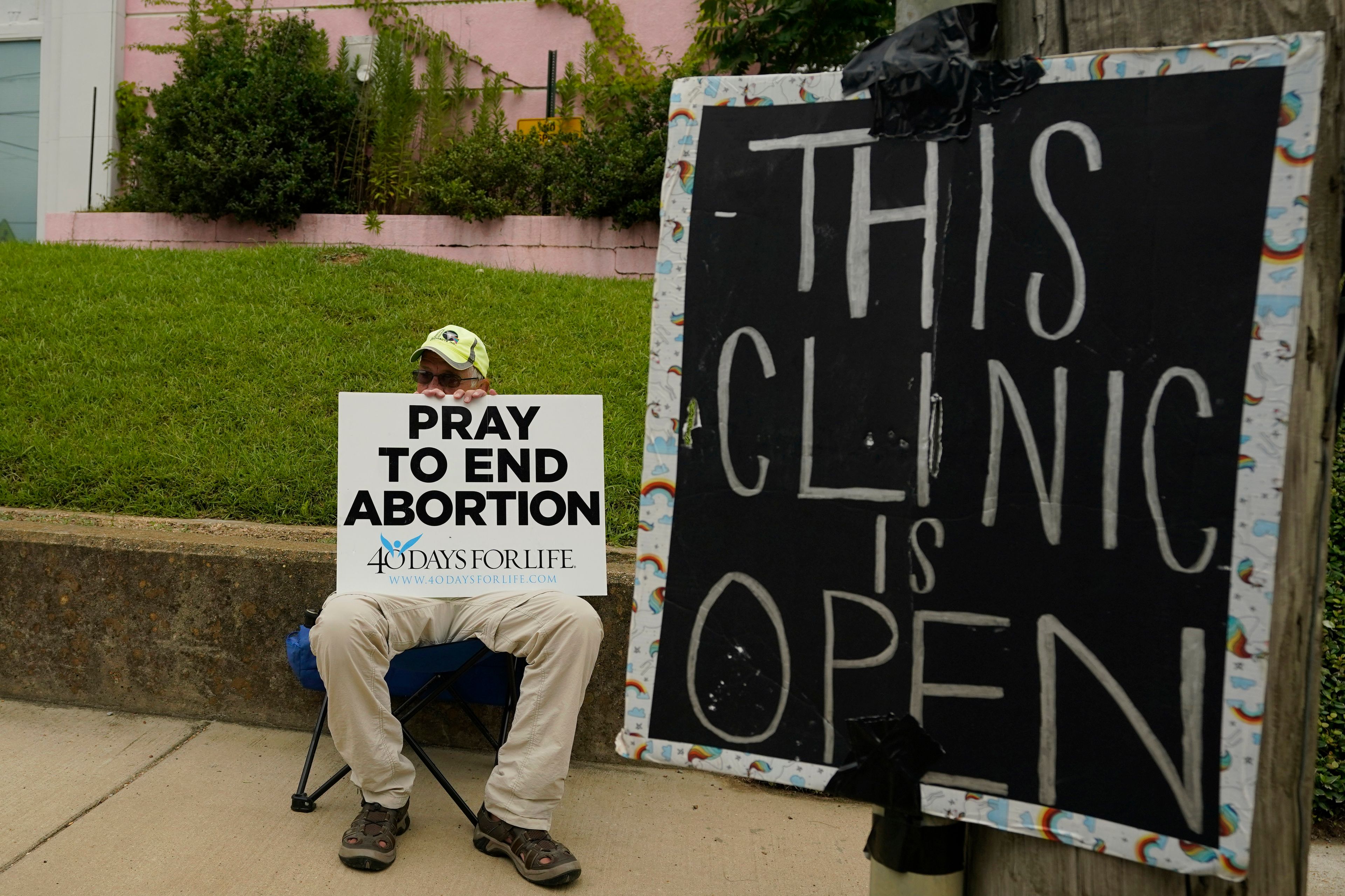 FILE - An anti-abortion supporter sits behind a sign that advises the Jackson Women's Health Organization clinic is still open in Jackson, Miss., Wednesday, July 6, 2022. (AP Photo/Rogelio V. Solis, File)