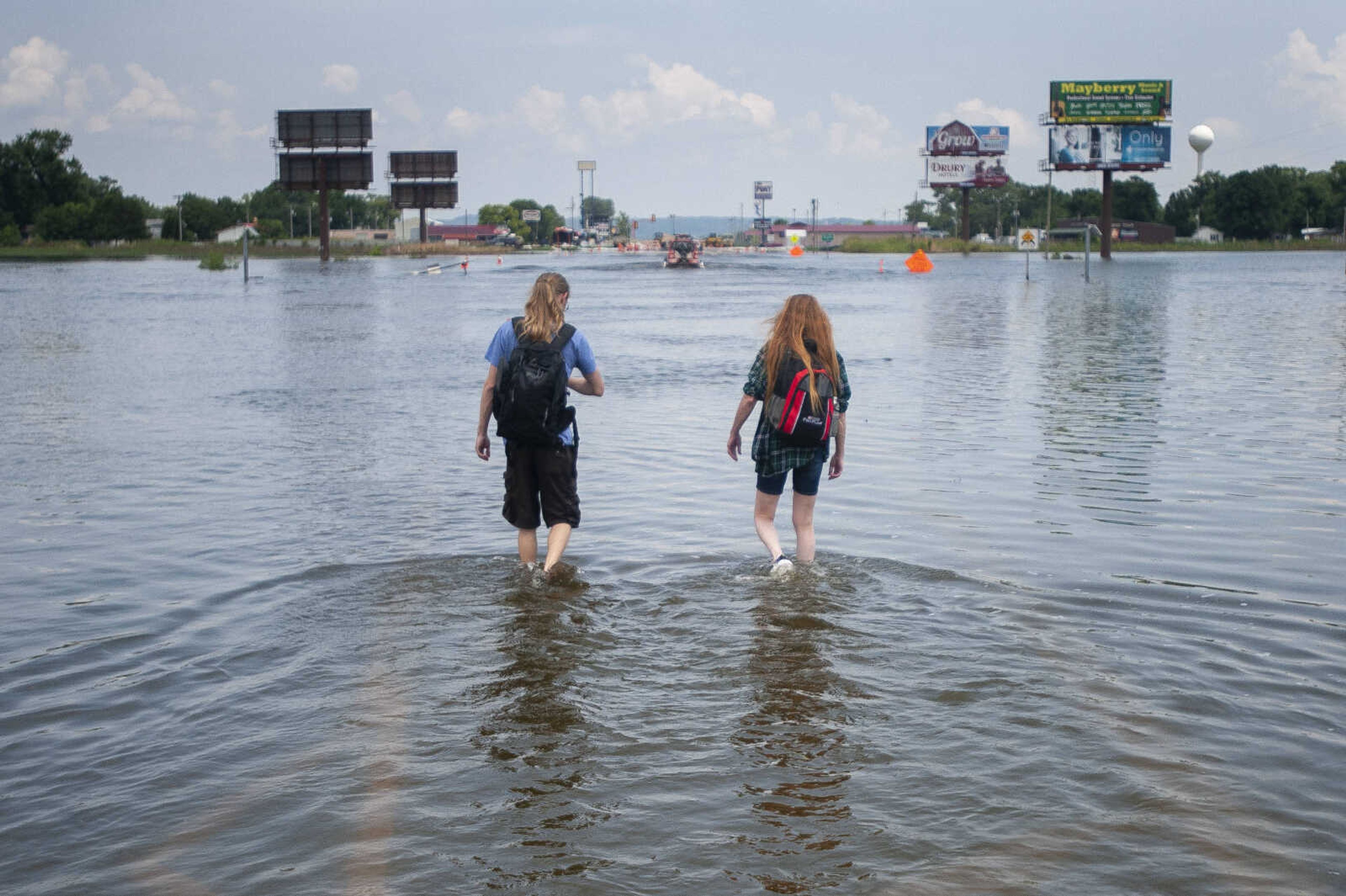 Cindy Laymon, right, and her son Jesse Laymon-Sheffer, both of East Cape Girardeau, Illinois, walk back to the community from their parked vehicle Tuesday, July 9, 2019, through a flooded portion of Illinois Route 146 between the Bill Emerson Memorial Bridge and the edge of East Cape Girardeau. The mother and son have been parking a vehicle at the edge of floodwaters to travel to work in Cape Girardeau. "We have come to work every day so it's at least two trips [through the water]," Cindy said of their routine for most days.