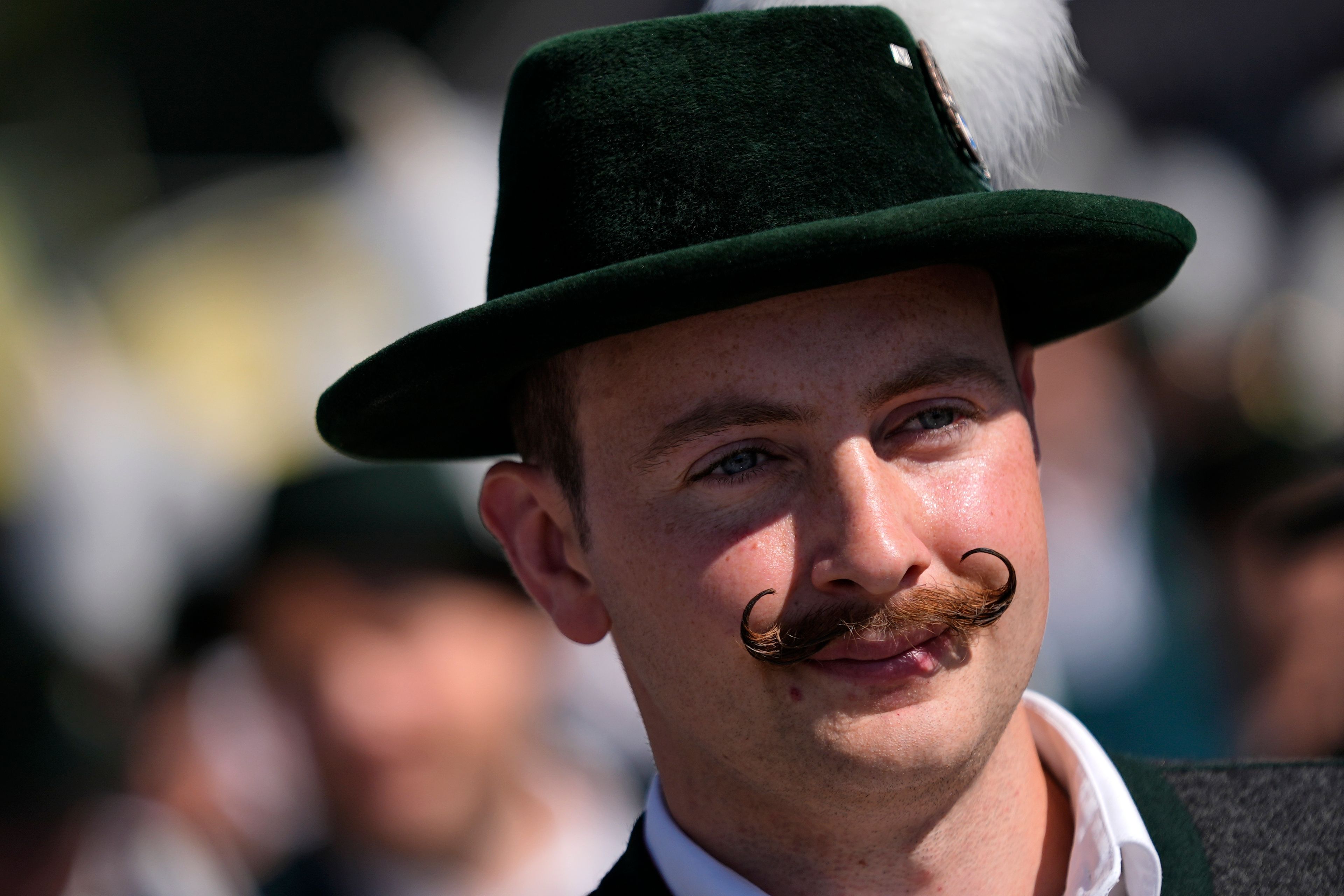 A visitor in traditional Bavarian clothes and a moustache attends the start of the 189th 'Oktoberfest' beer festival in Munich, Germany, Saturday, Sept. 21, 2024. (AP Photo/Matthias Schrader)