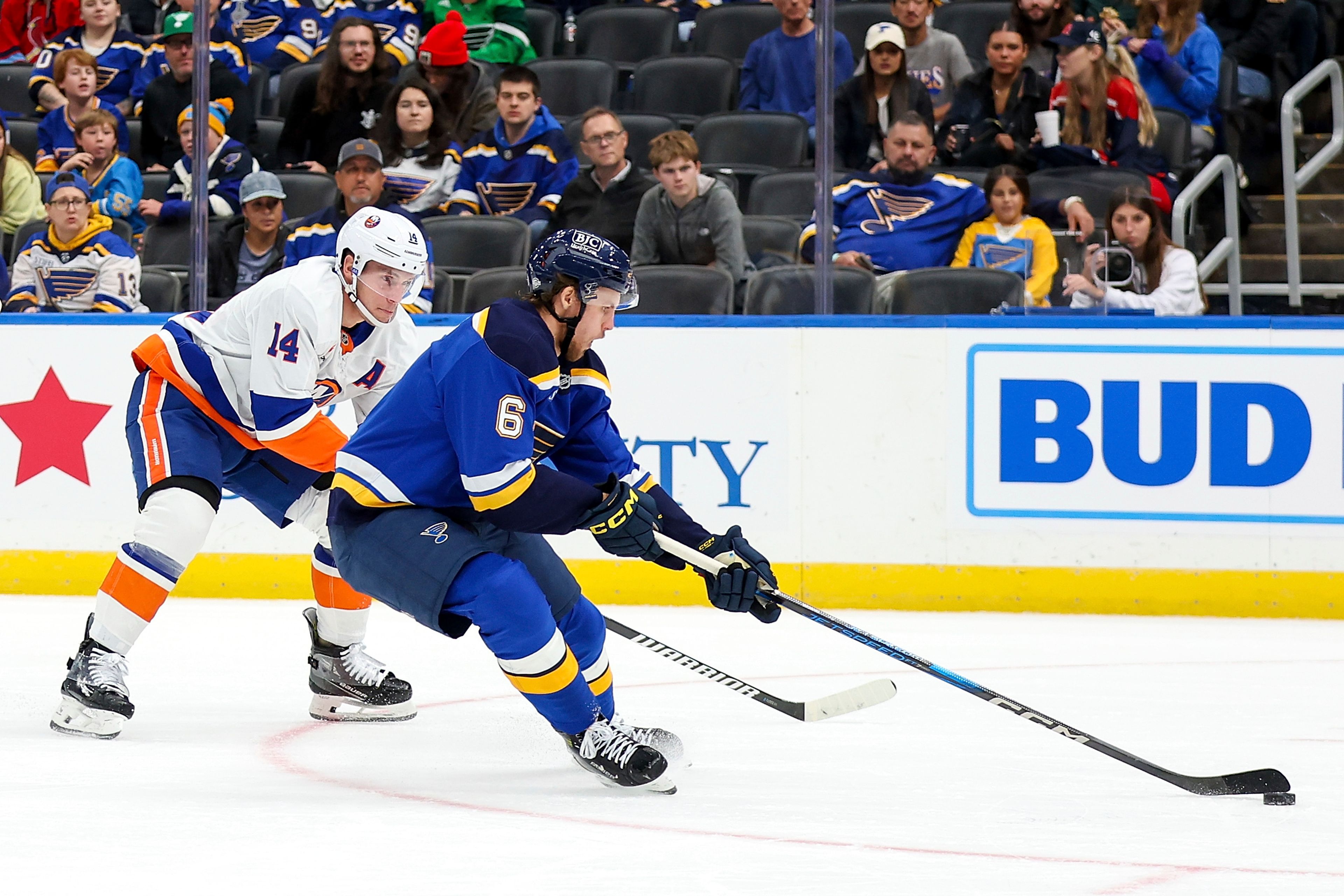 St. Louis Blues' Philip Broberg (6) handles the puck while under pressure from New York Islanders' Bo Horvat (14) during the first period of an NHL hockey game Thursday, Oct. 17, 2024, in St. Louis. (AP Photo/Scott Kane)