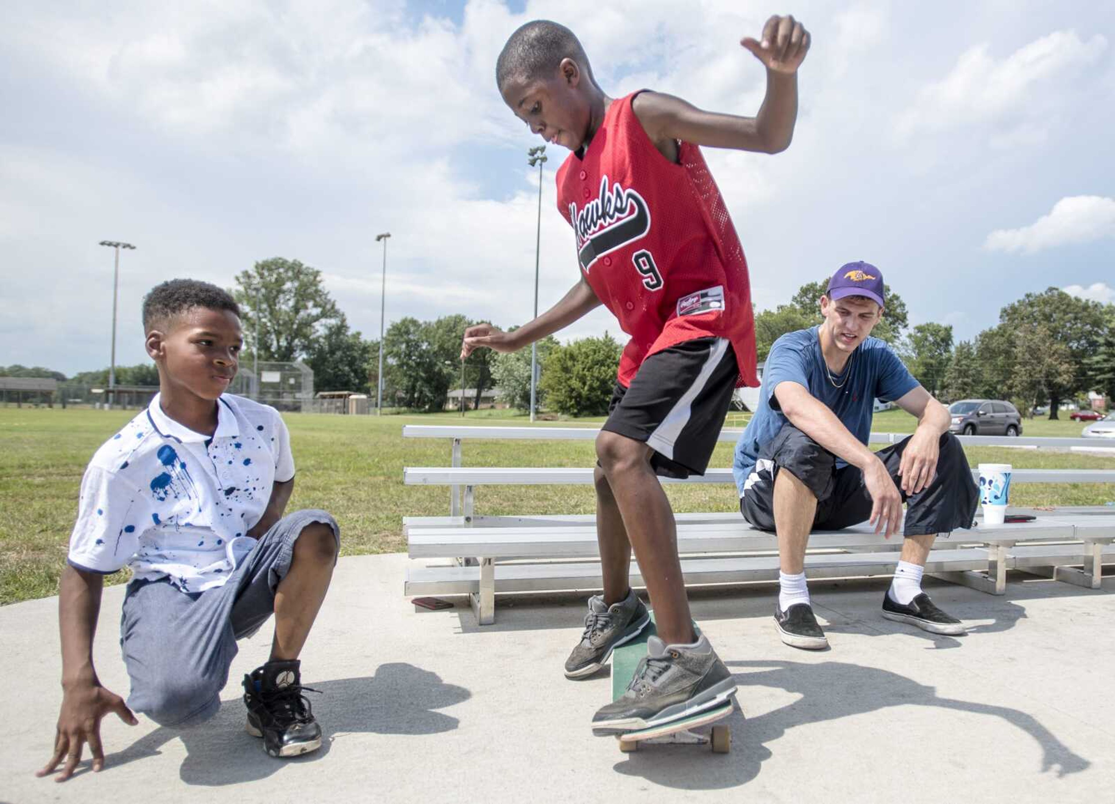 While taking a break from skating, Carson Ketcher, right, watches and Trey Howard, 11, left, watch Delijah White, 12, attempt to ride Ketcher's skateboard Sunday, Aug. 18, 2019, at Wheel Park in Cape Girardeau. White said he prefers riding bicycles.