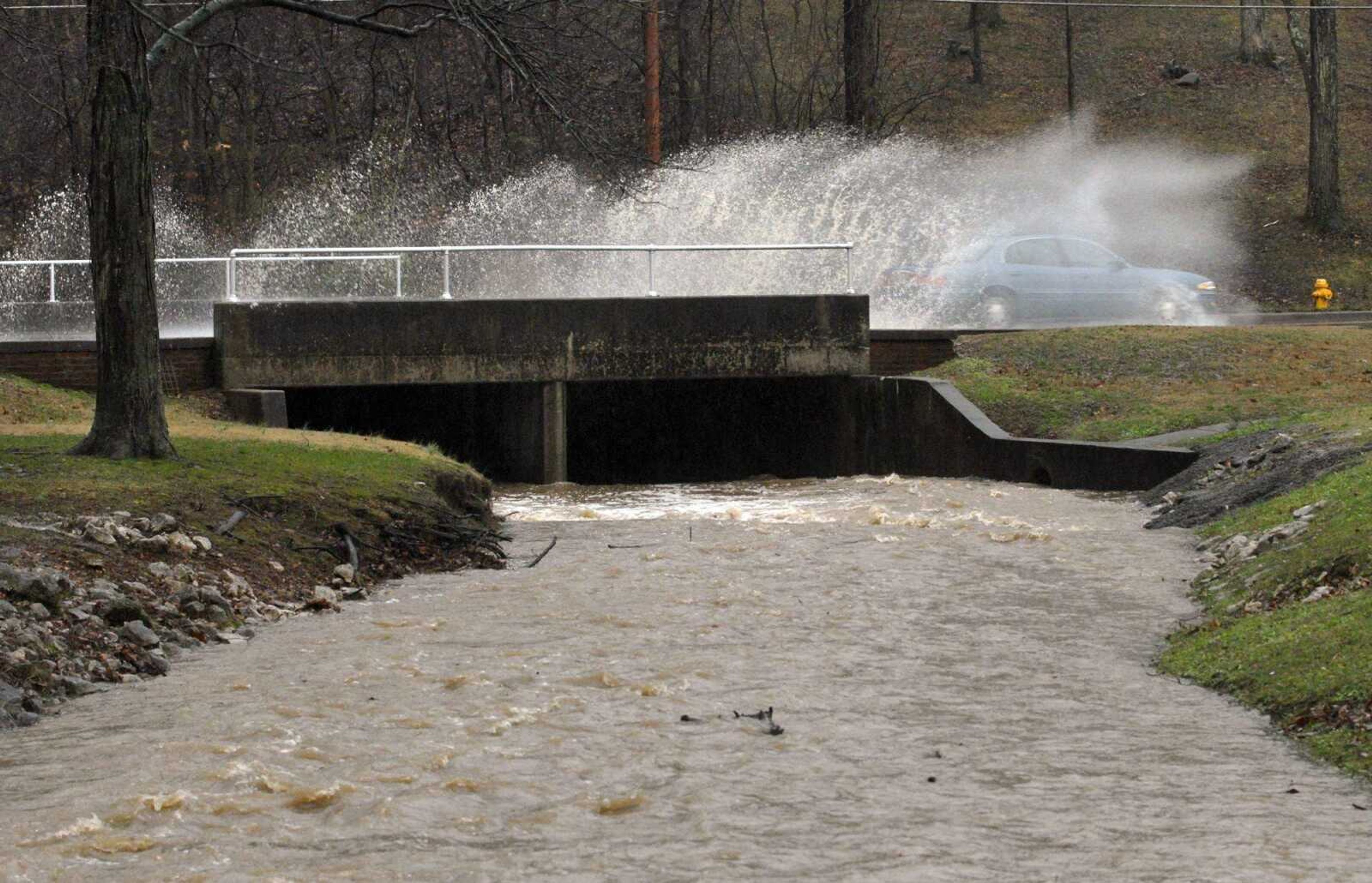 A motorist on Cape Rock Drive splashed over the swollen Walker Branch that runs through Dennis Scivally Park during heavy rain Tuesday. (Fred Lynch)