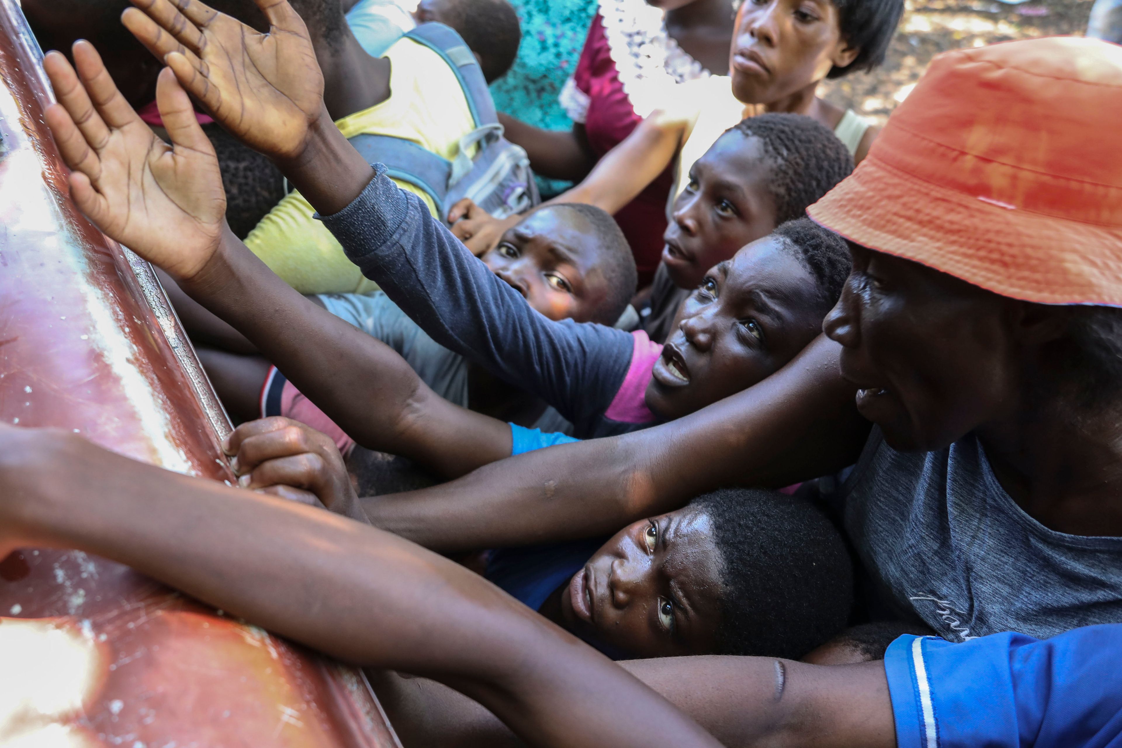 People displaced by armed attacks receive food from a nongovernmental organization in Saint-Marc, Haiti, Sunday, Oct. 6, 2024. (AP Photo/Odelyn Joseph)