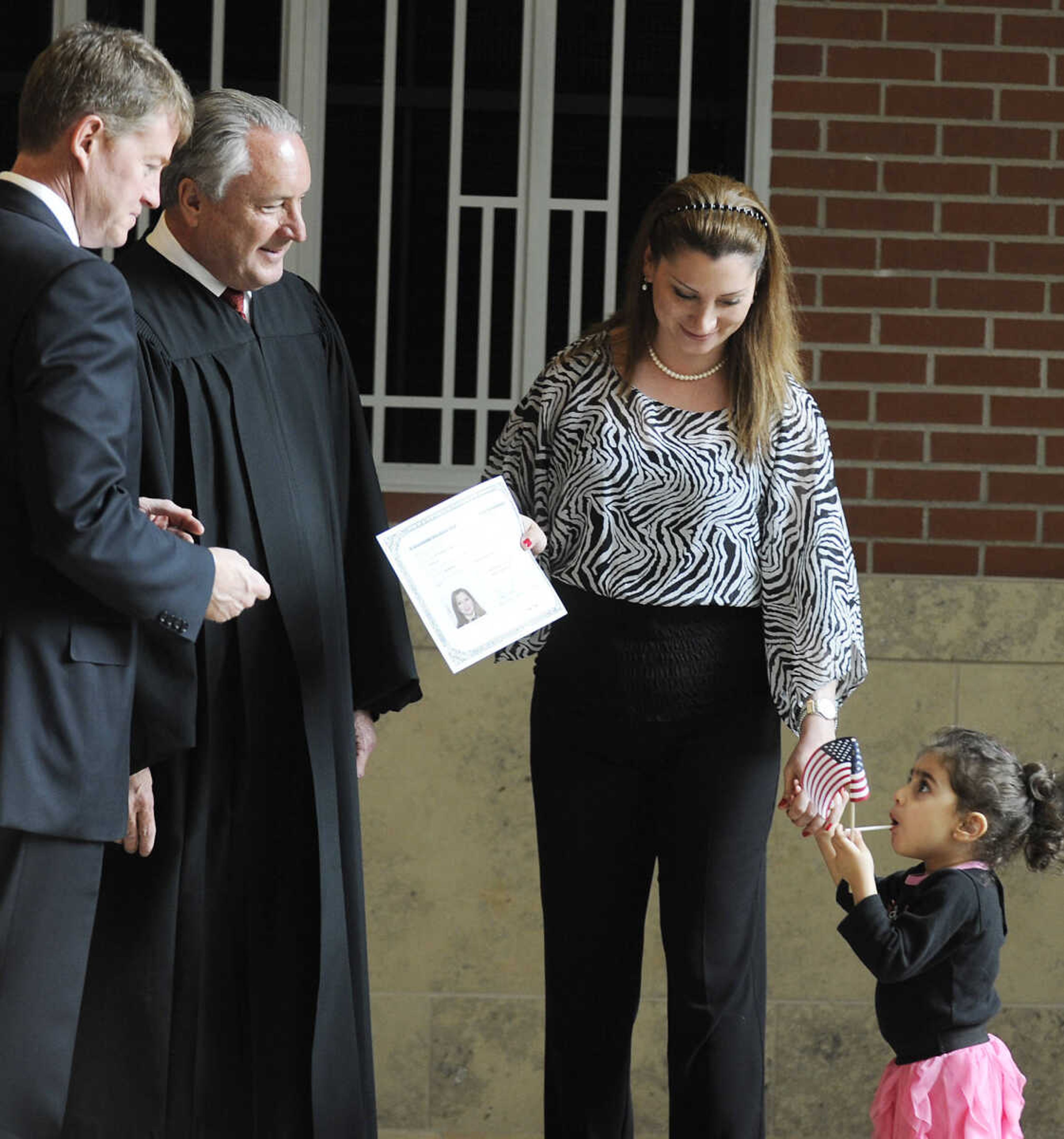 Pilar Nabil Eid, who immigrated to the U.S. from Syria, collects her certificate of naturalization from Missouri Attorney General Chris Koster, left, and U.S. District Court Judge Stephen N. Limbaugh Jr. with her daughter Alexandra Tannous, 2, after a naturalization ceremony Wednesday, May 1, at the Rush H. Limbaugh Sr. U.S. Courthouse in Cape Girardeau. Limbaugh administered the oath to 29 people from 11 countries, making them U.S. citizens, during the ceremony.