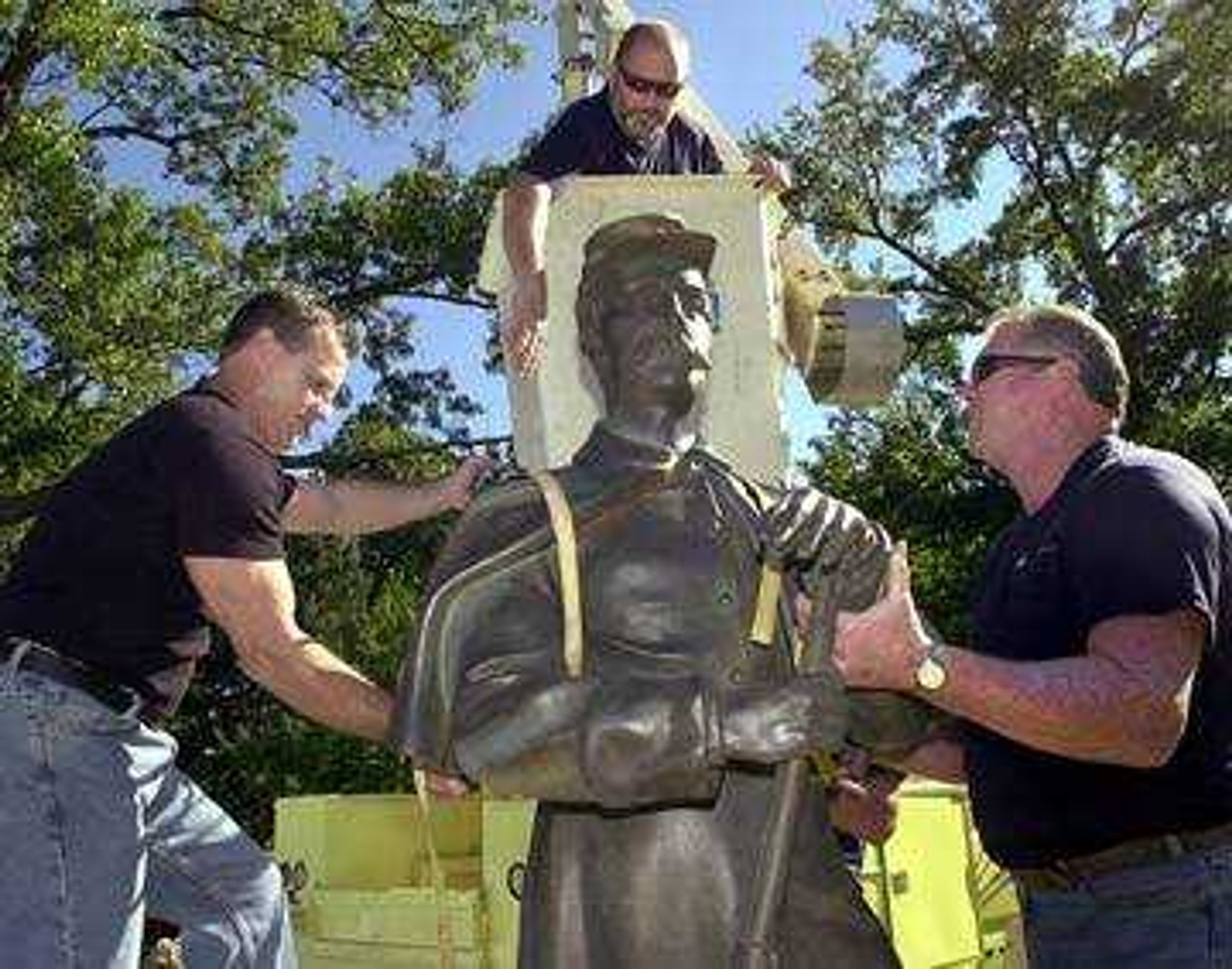 Alan Gibson, left, and Don McQuay attached straps to the Civil War soldier as Shannon Steger waited to lift the statue to the top of the fountain at Common Pleas Courthouse Park.