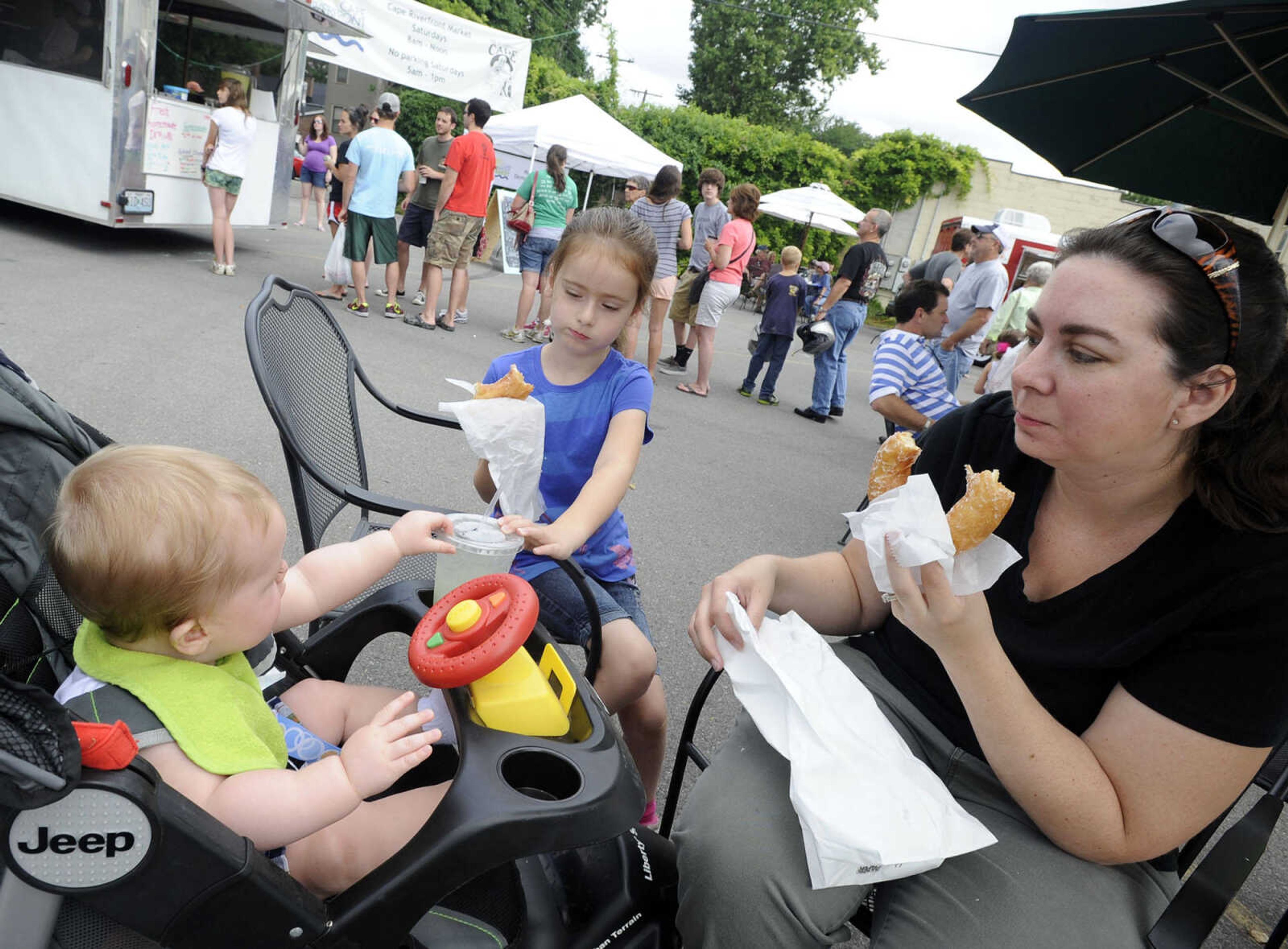 FRED LYNCH ~ flynch@semissourian.com
Holly French and her daughter, Sydney, 5, enjoy homemade doughnuts as son Alex reaches for a cold drink at the Cape Riverfront Market Saturday, July 6, 2013 in Cape Girardeau.