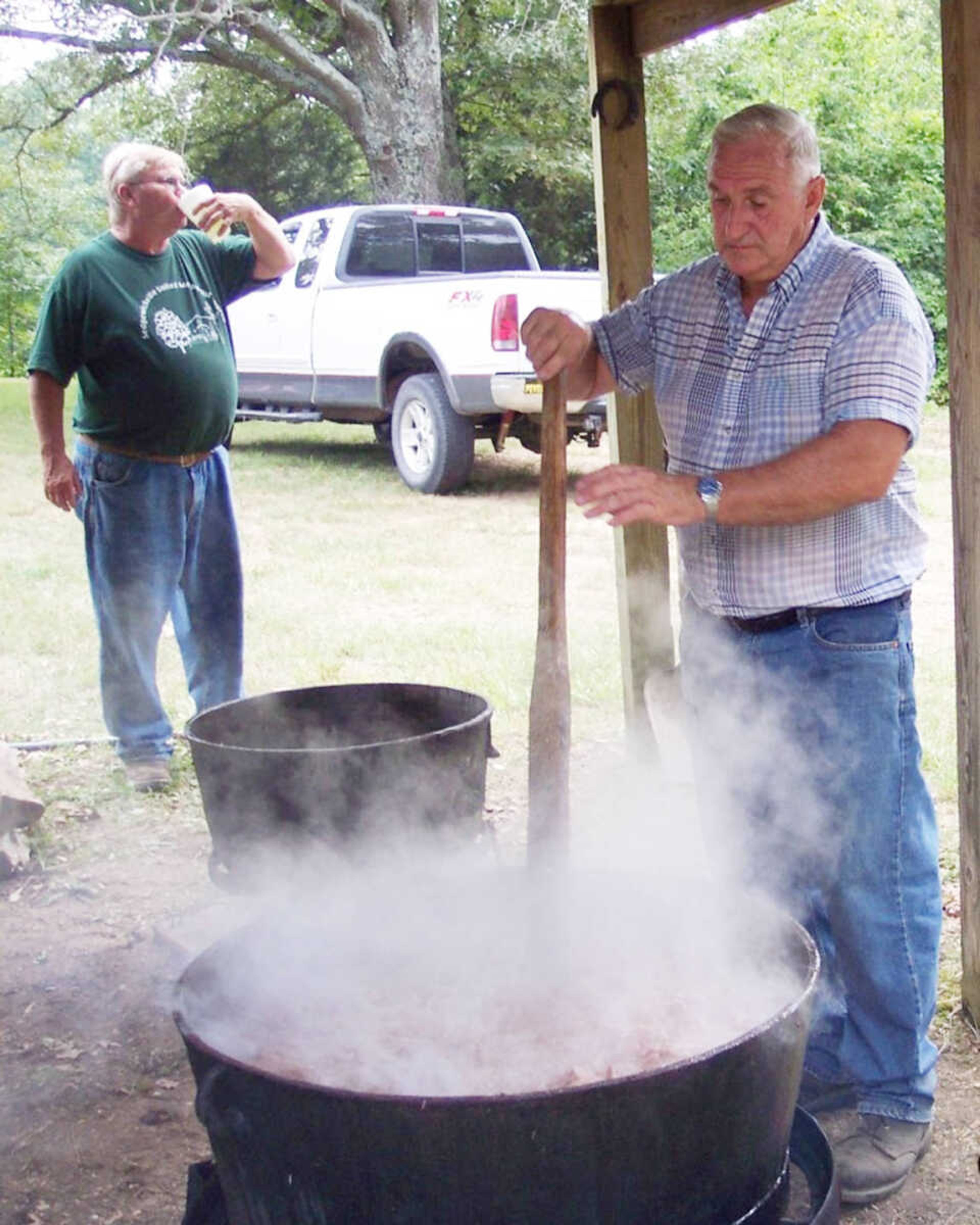 Bob Maes takes a break while Loy Shrum  stirs the kettle beef for a  past church dinner.